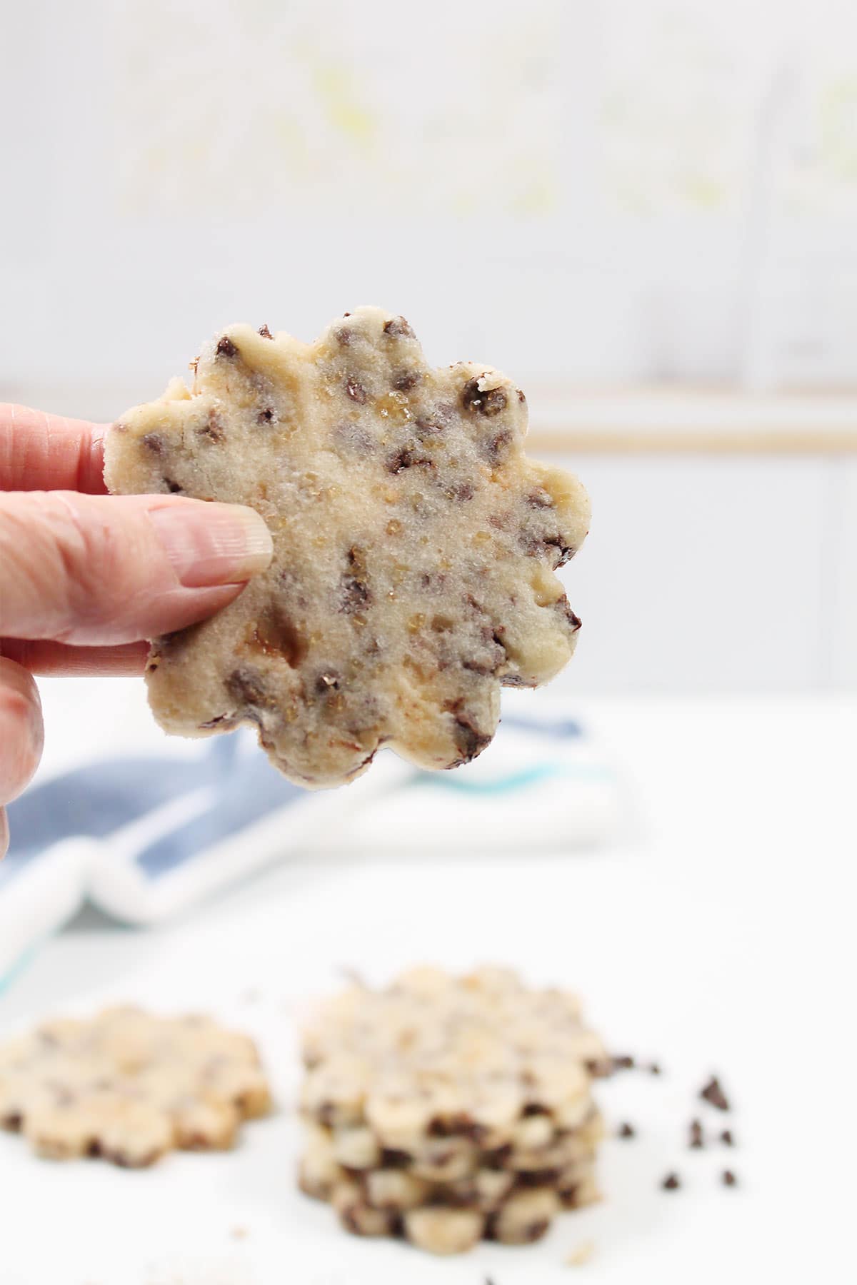 Holding toffee shortbread cookie over stack of cookies.