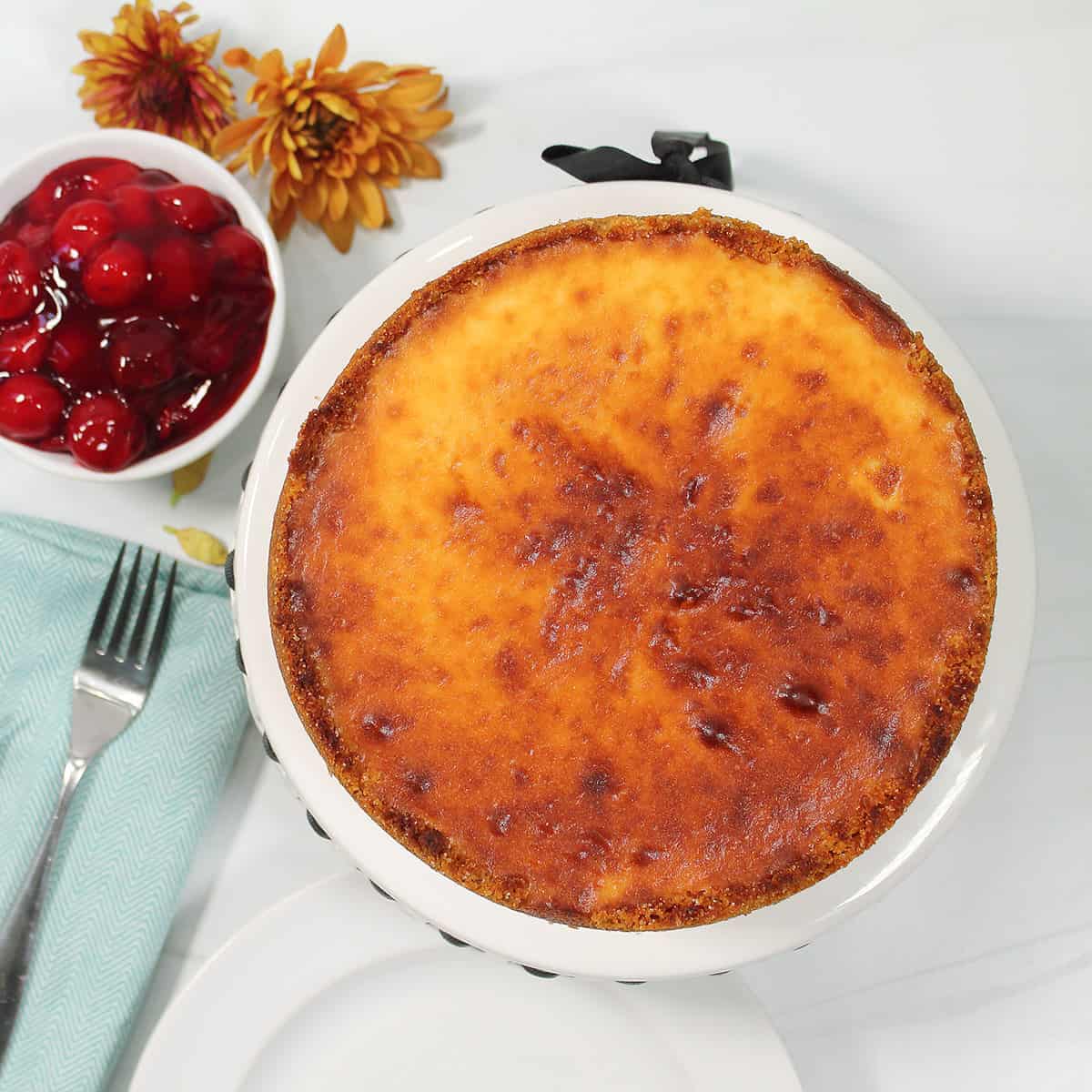 Overhead of air fryer basque cheesecake with bowl of cherries.