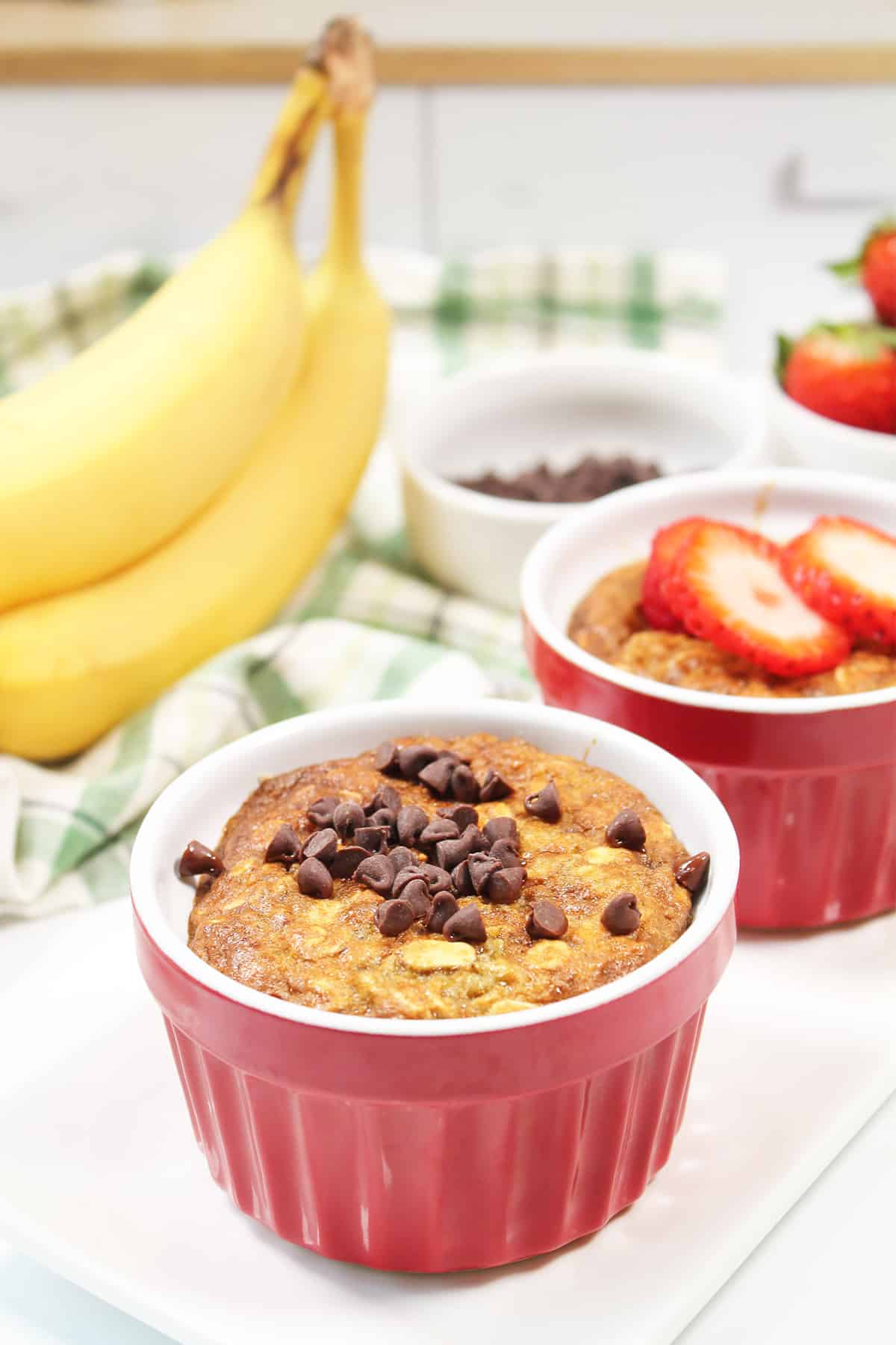 Two air fryer baked oats in red ramekins with toppings.
