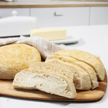 Sliced loaf of bread with buttered slice in front.