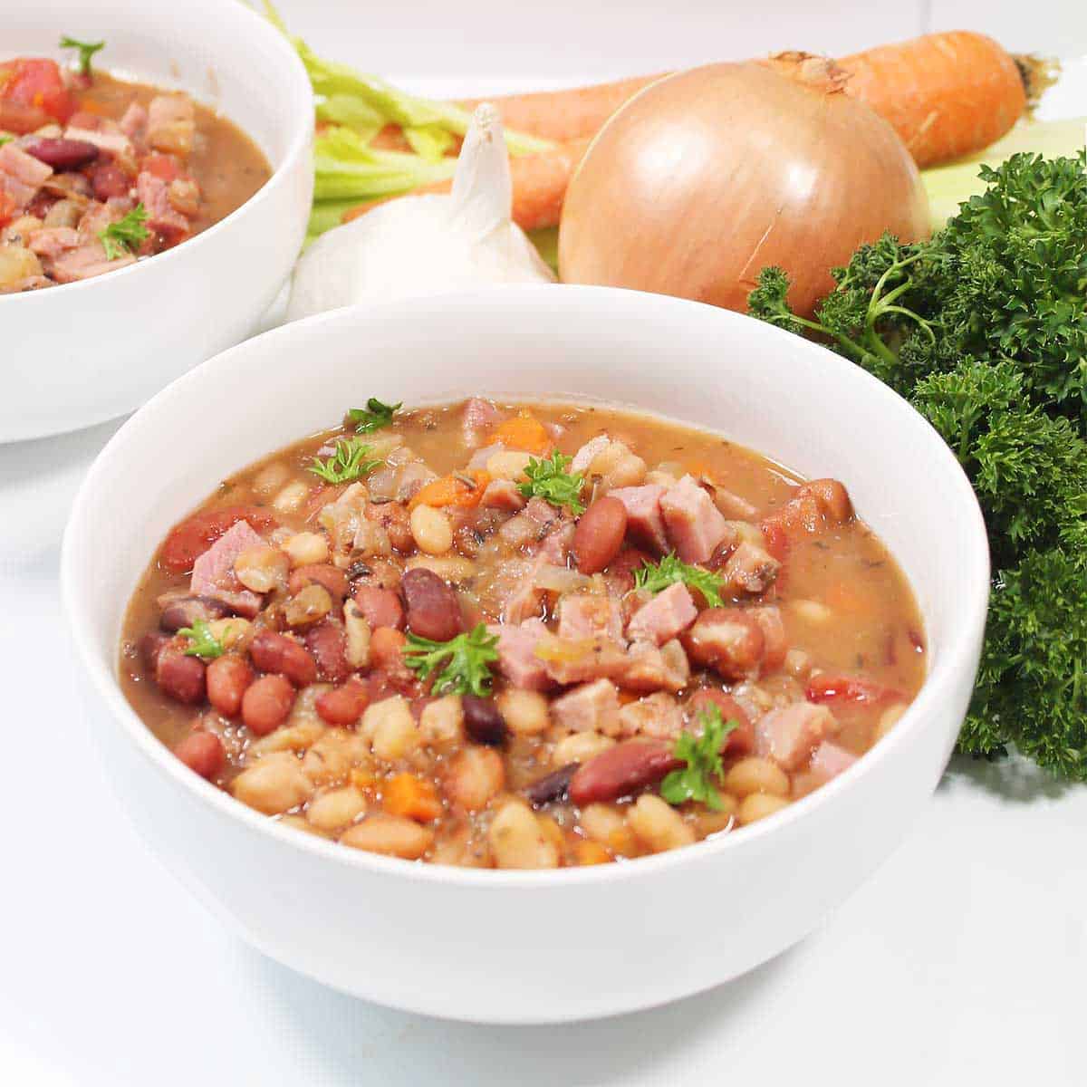 Bowls of soup next to vegetables.