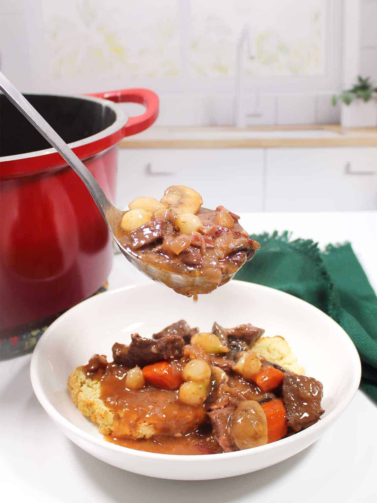 Ladleful of beef mushroom stew over serving bowl.