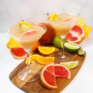 Two grapefruit vodka martinis with sliced fruit.