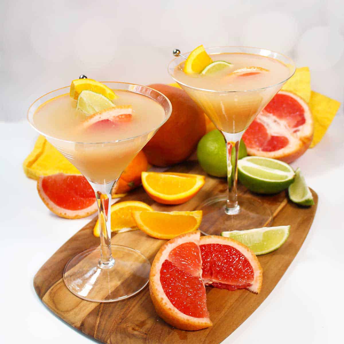Two grapefruit vodka martinis with sliced fruit.