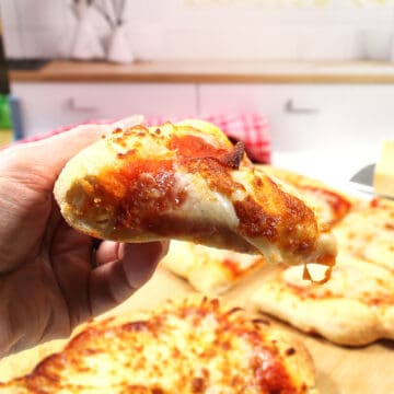 Closeup holding slice of homemade pizza in air fryer.
