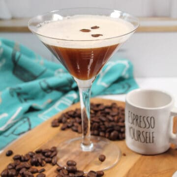 Single cocktail on wooden board with espresso cup.