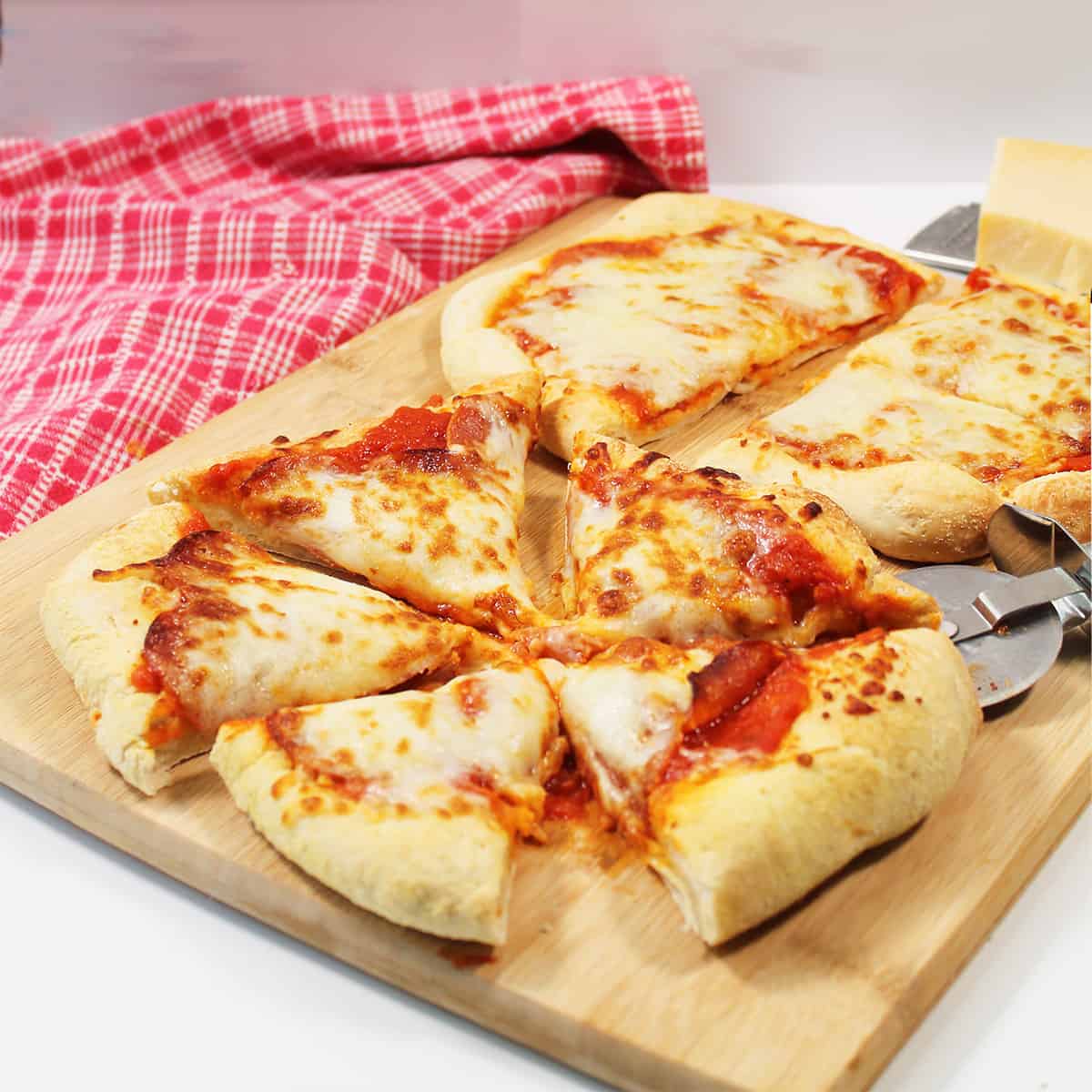 Sliced pizza with red checkered towel.