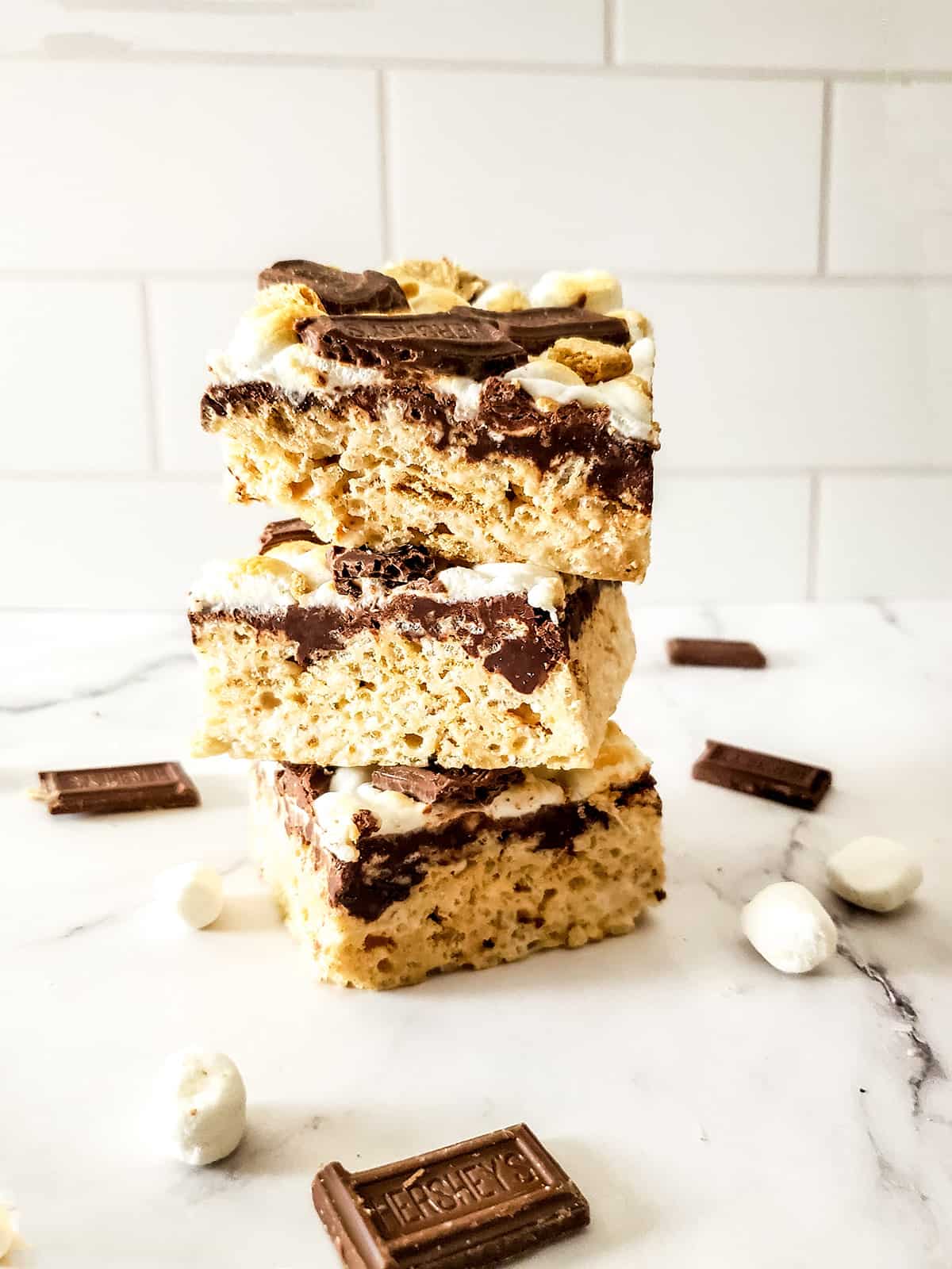 Stack of s'mores krispie treats with marshmallows and chocolate pieces.
