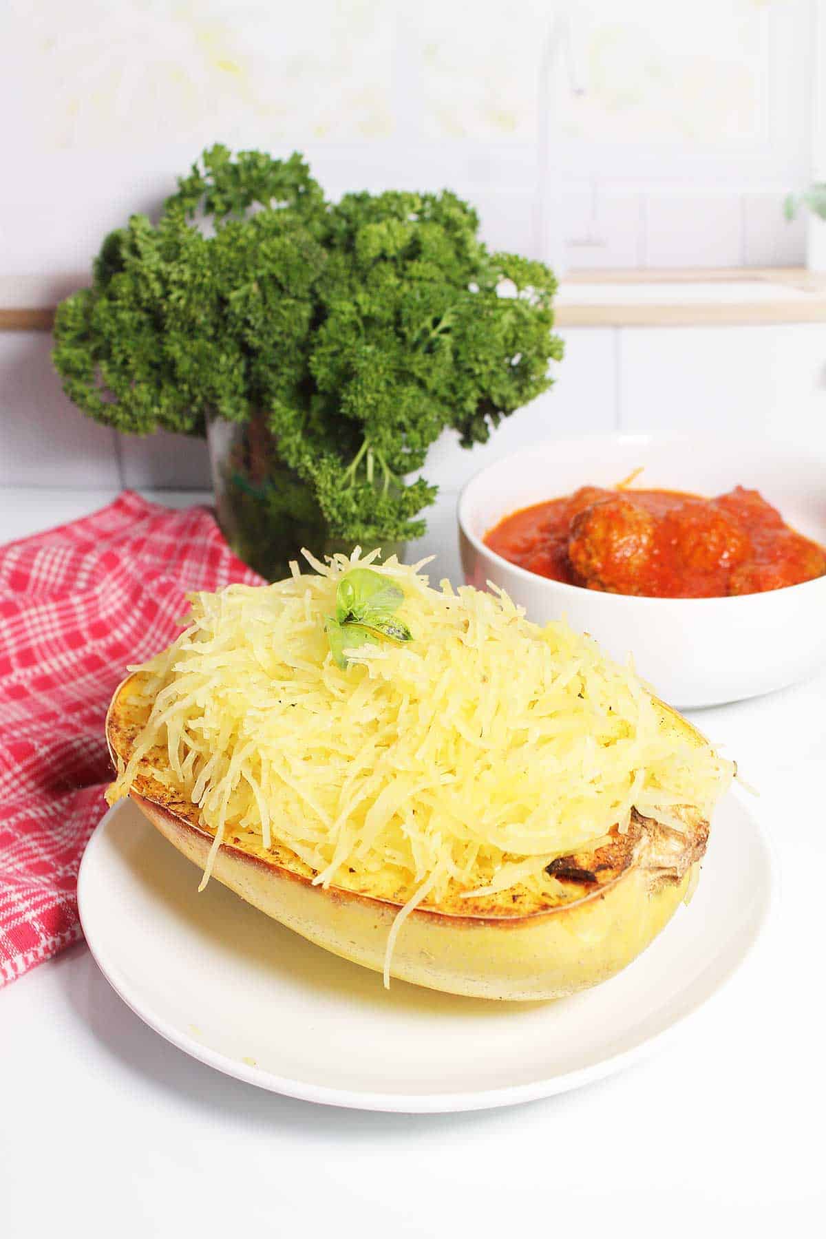 Air Fryer Spaghetti Squash in squash bowl with meatballs in back.