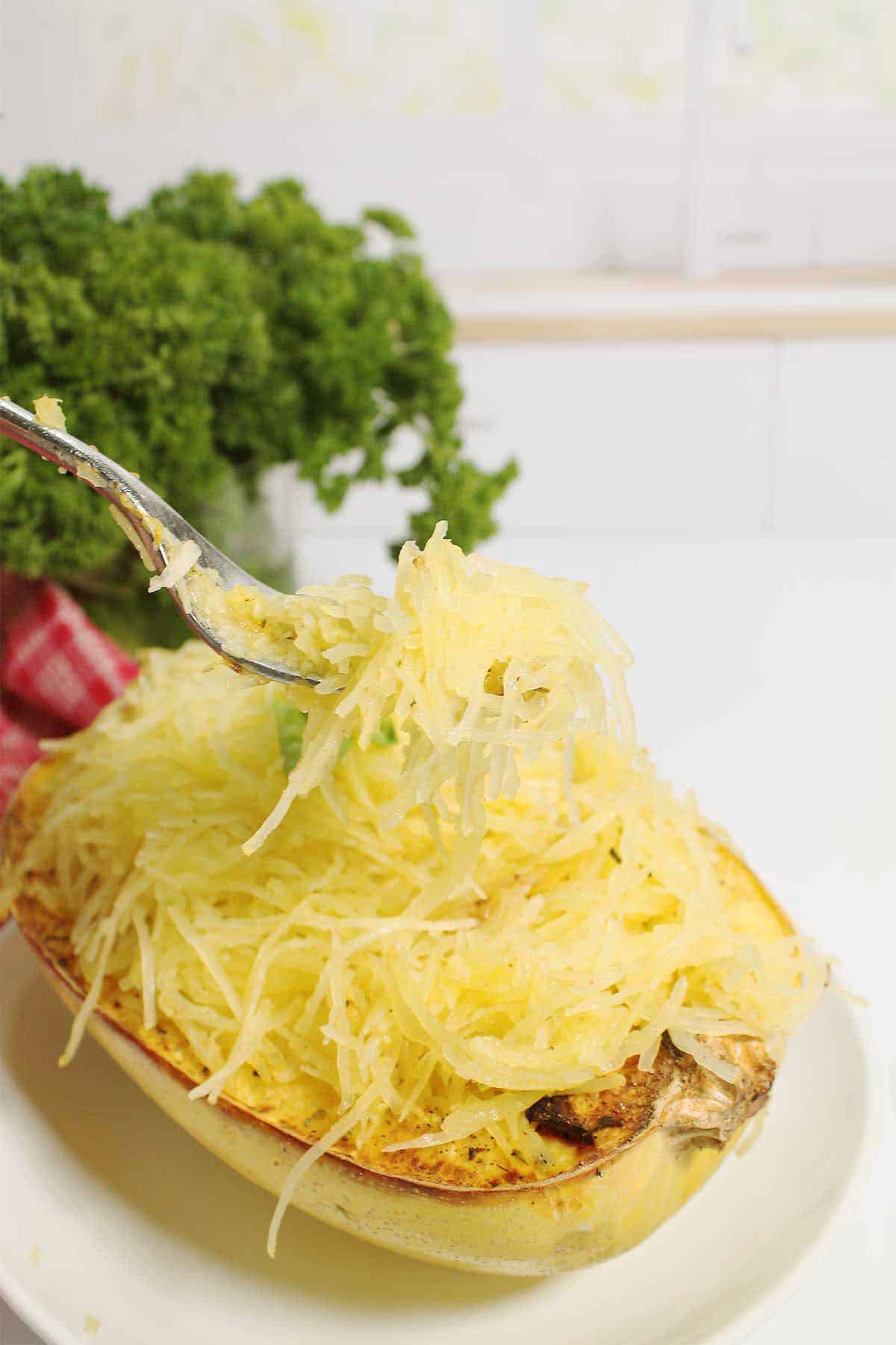 Strands of spaghetti squash on fork over bowl of squash.