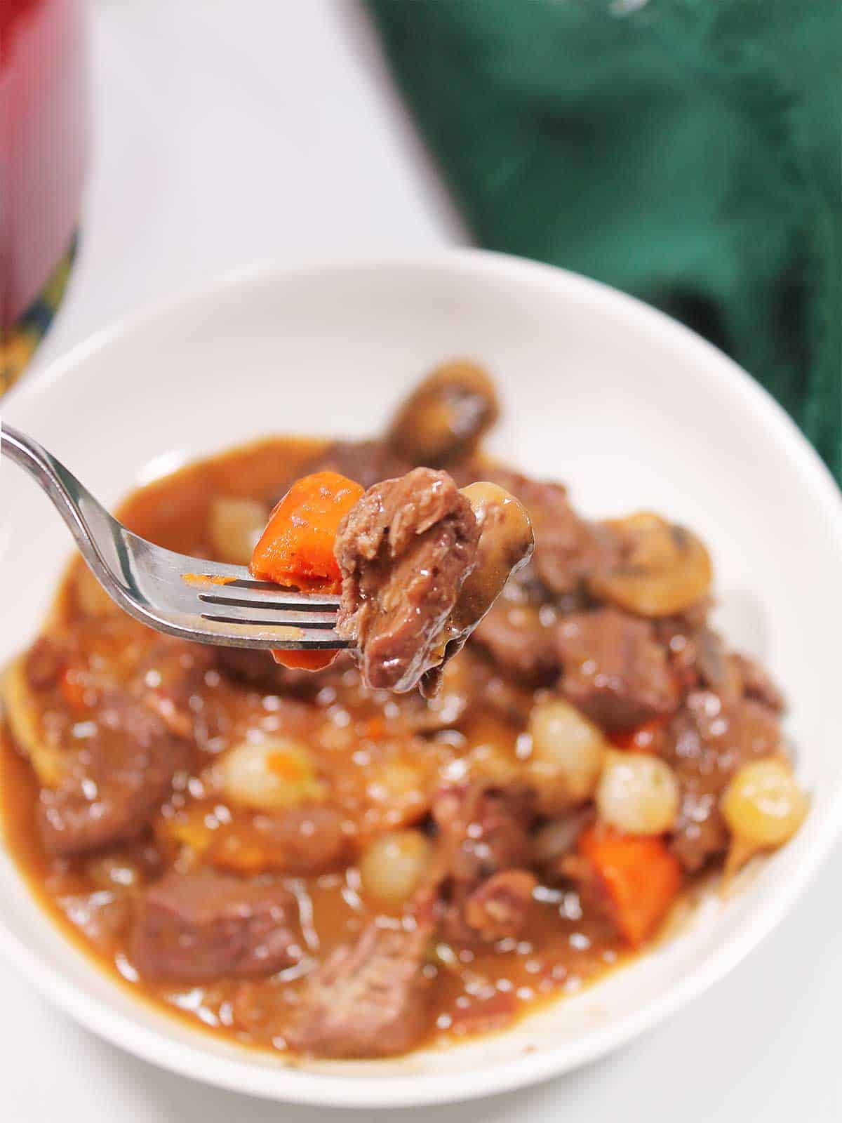 Bite of stew on fork above bowl.