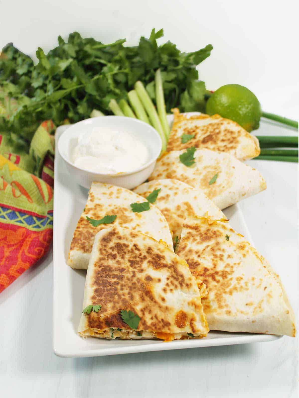 Platter of buffalo quesadillas with sour cream and celery sticks.