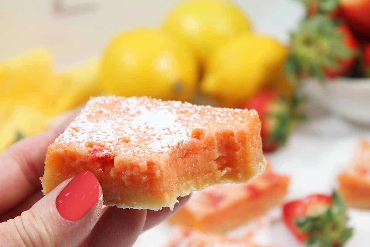 Holding a pink version of a strawberry lemon bar.