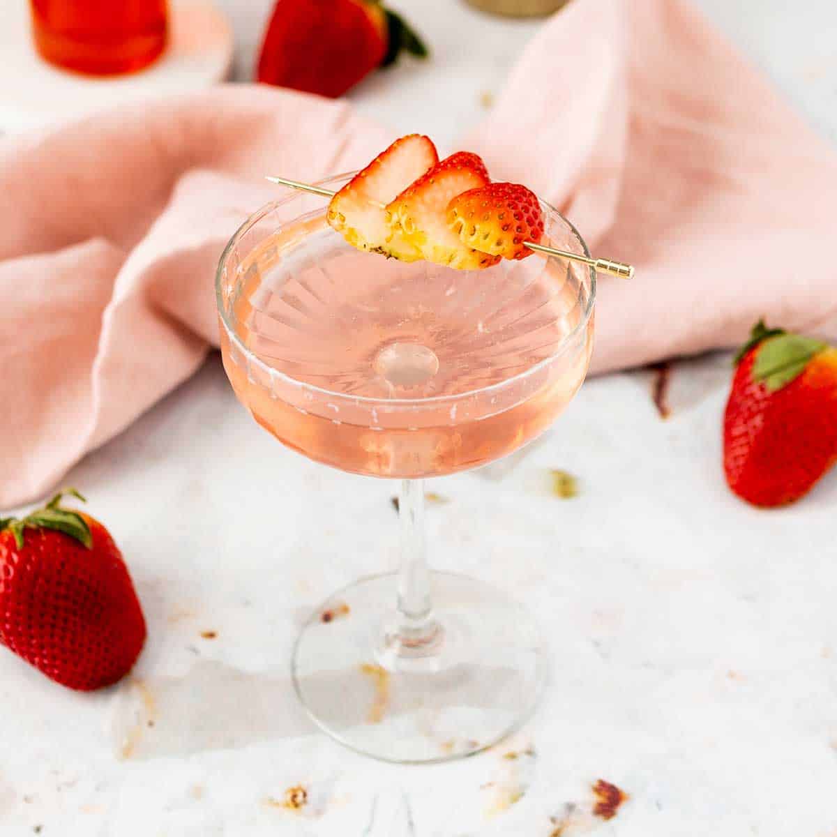 Cocktail with a garnish of strawberries on a skewer.