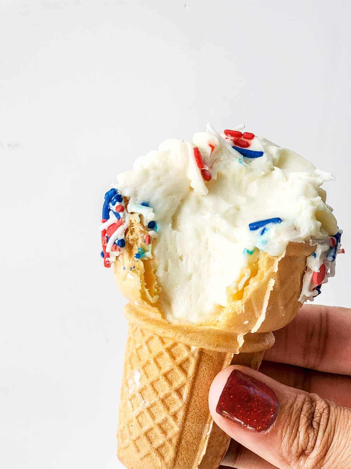 Holding an ice cream cone with bite out of it.