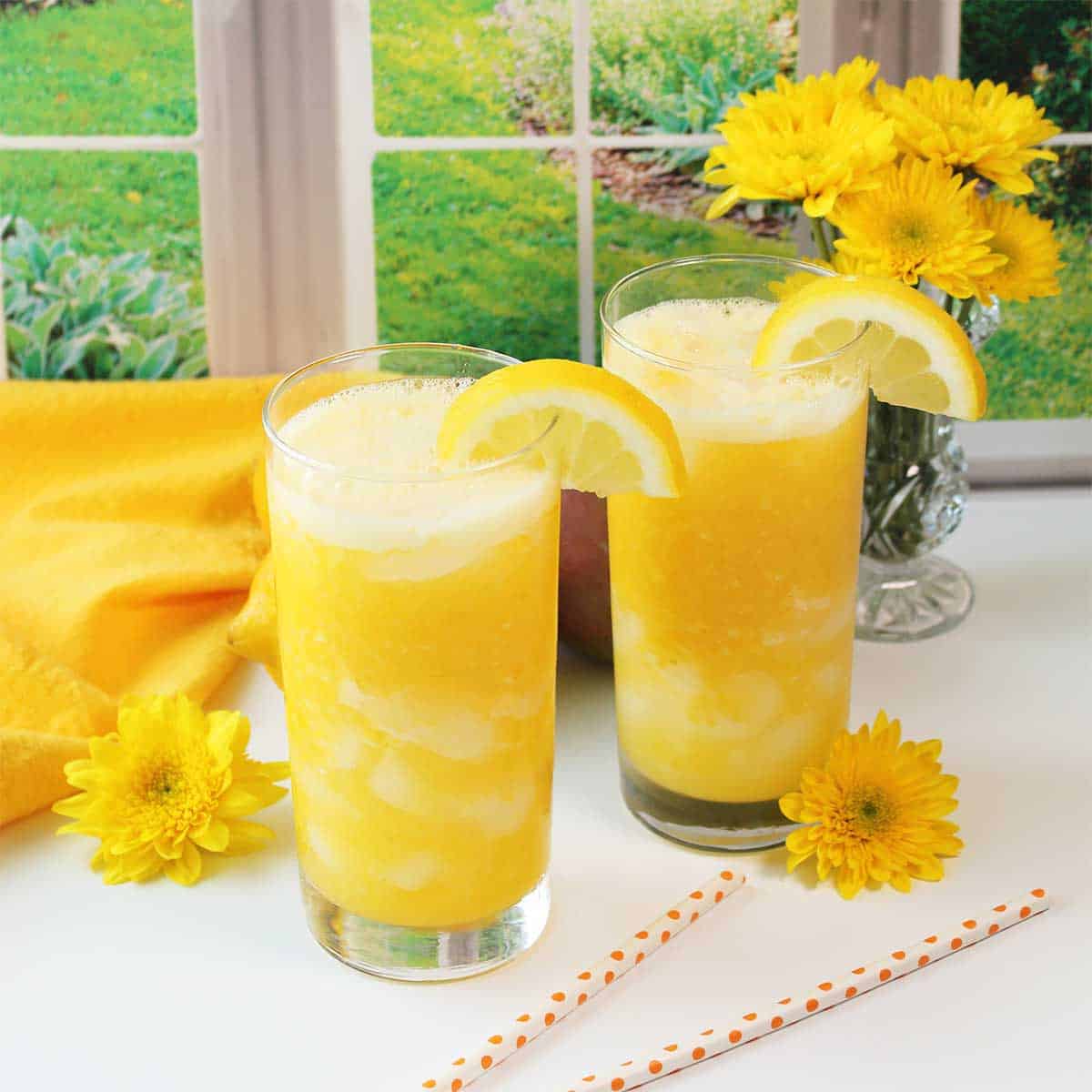 Mango lemonade in glasses with lemon garnish.