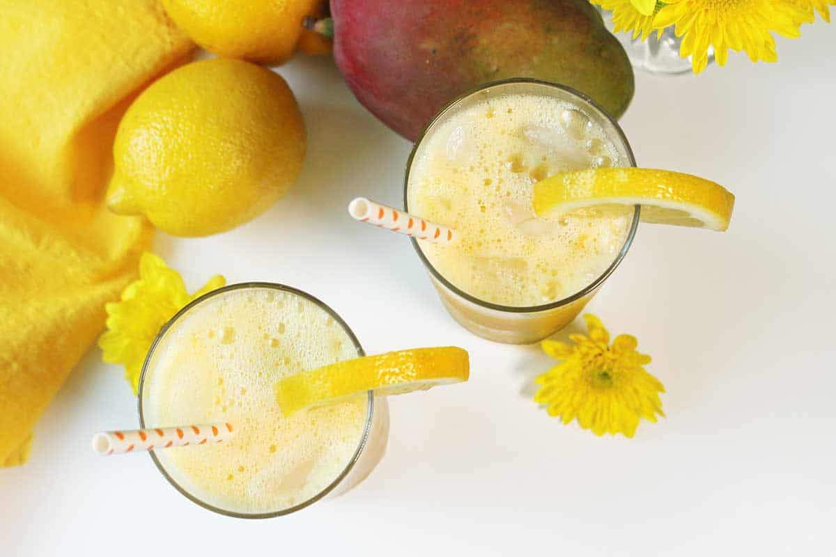 Overhead of two glasses of frozen mango lemonade showing frothiness.