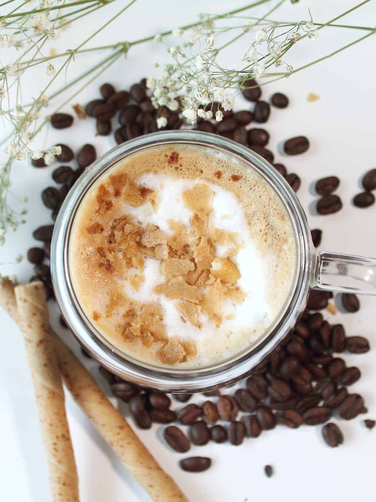 Overhead of latte surrounded by espresso beans.