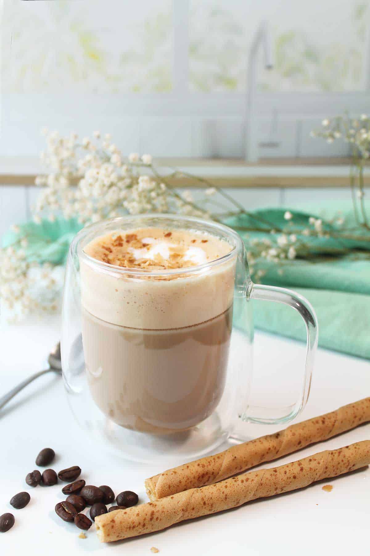 Pistachio latte with cookie crumbs on top on counter.