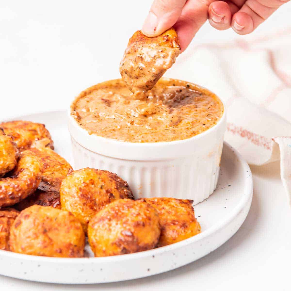 Air Fryer Pizza Bites on plate, dipping one into creamy marinara.