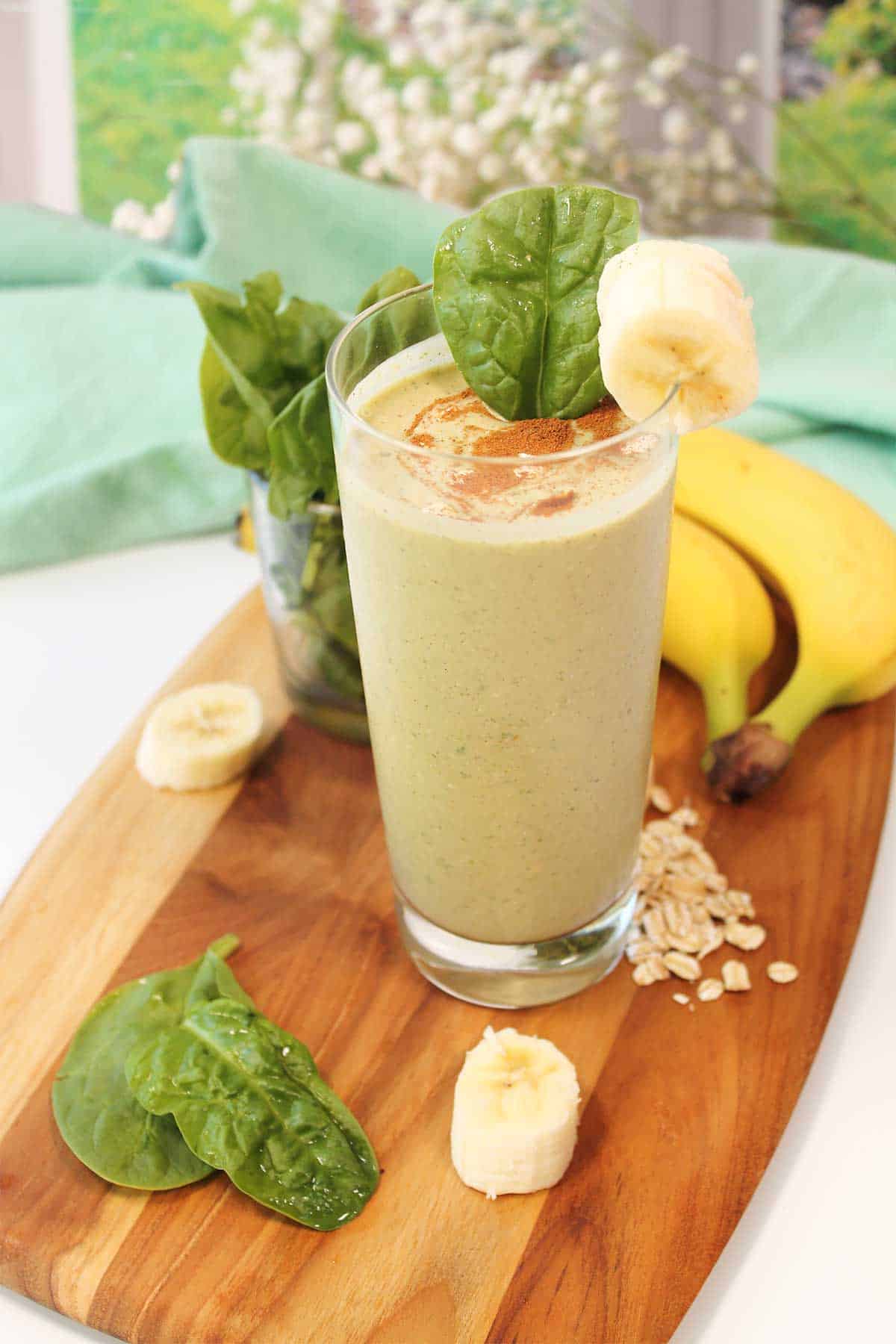 Banana Oatmeal Smoothie in tall glass on wooden board.