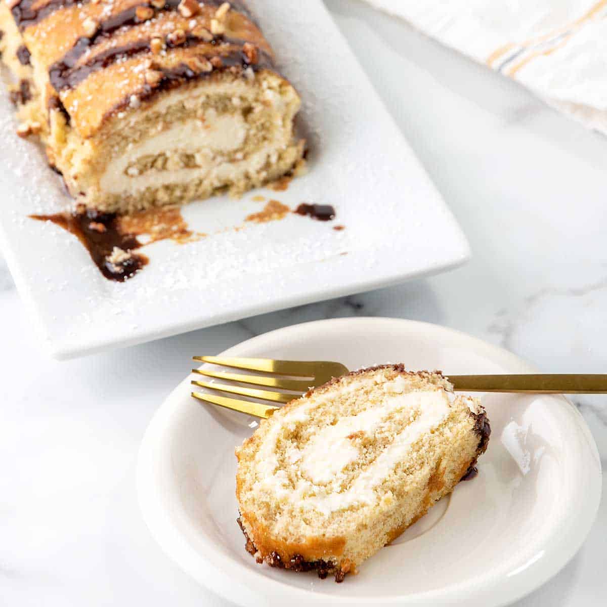 Slice of banana cake roll on plate with roll in back.