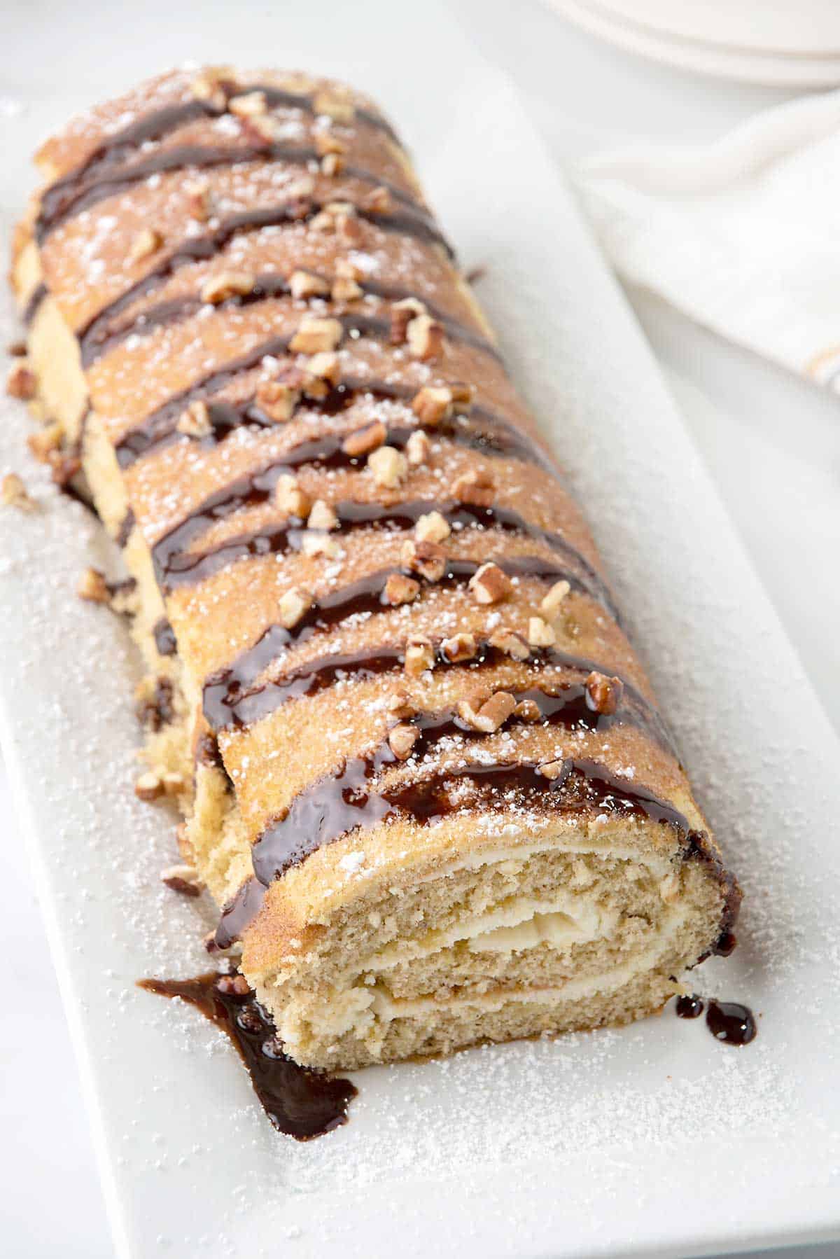 Banana Roll on platter with drizzle of chocolate and sprinkle of nuts.