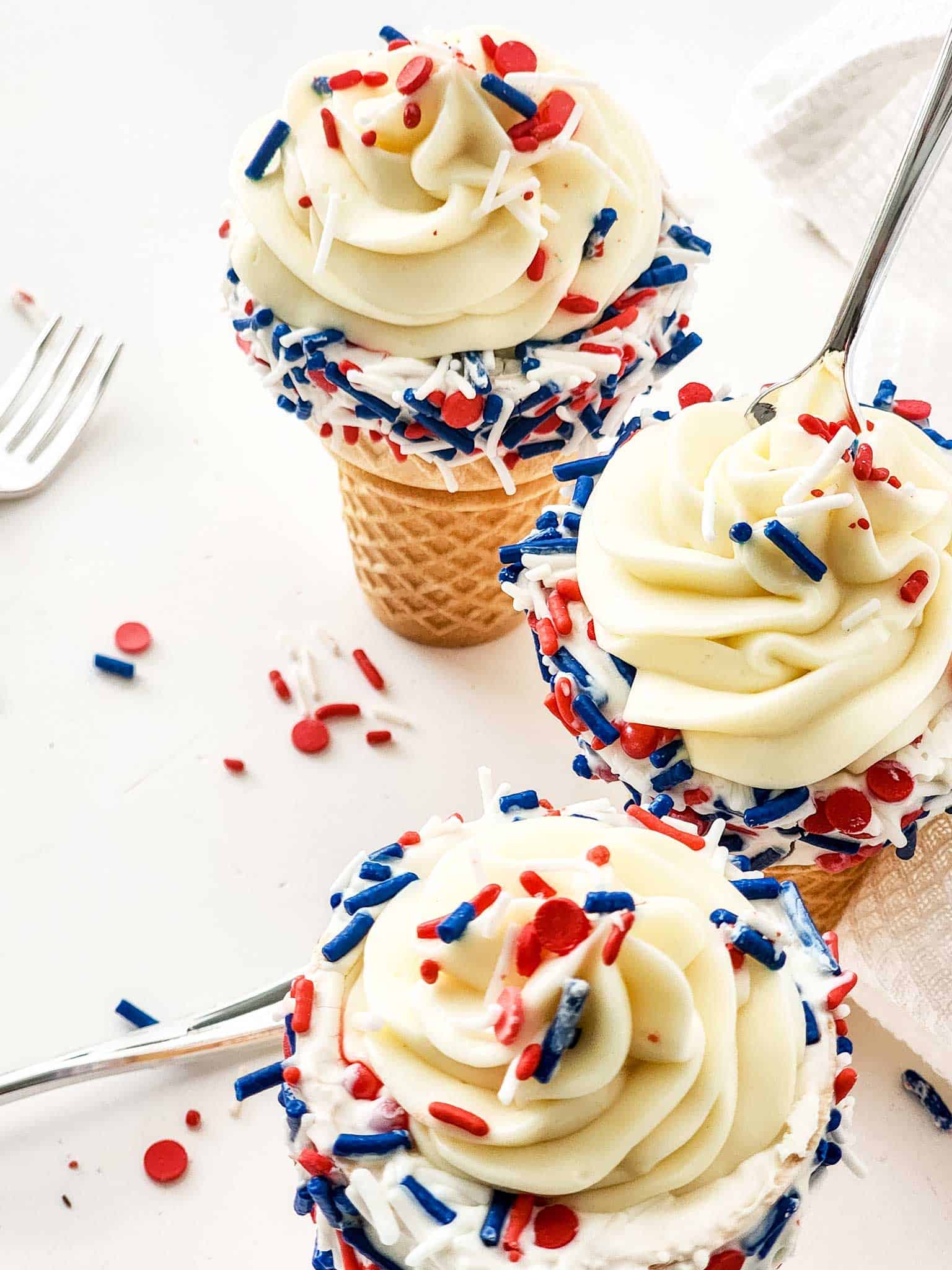 Overhead of cheesecake cones with sprinkles and a spoon.