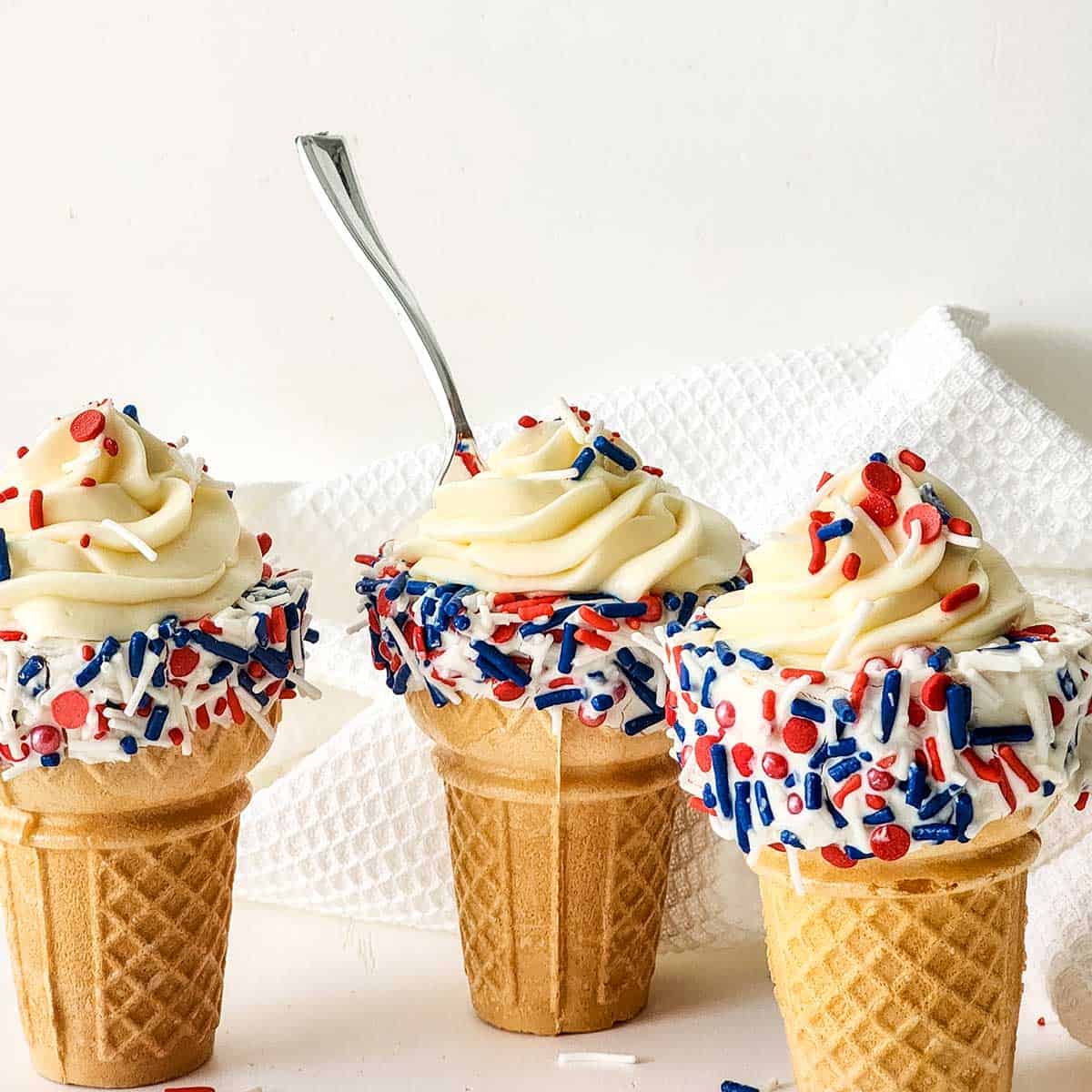 Three cheesecake mousse cones with spoon in one.