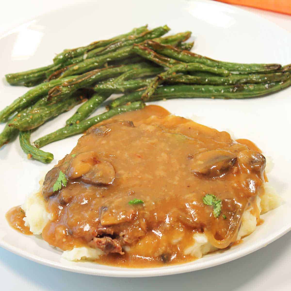 Closeup of plated crock pot cube steak and gravy with asparagus.