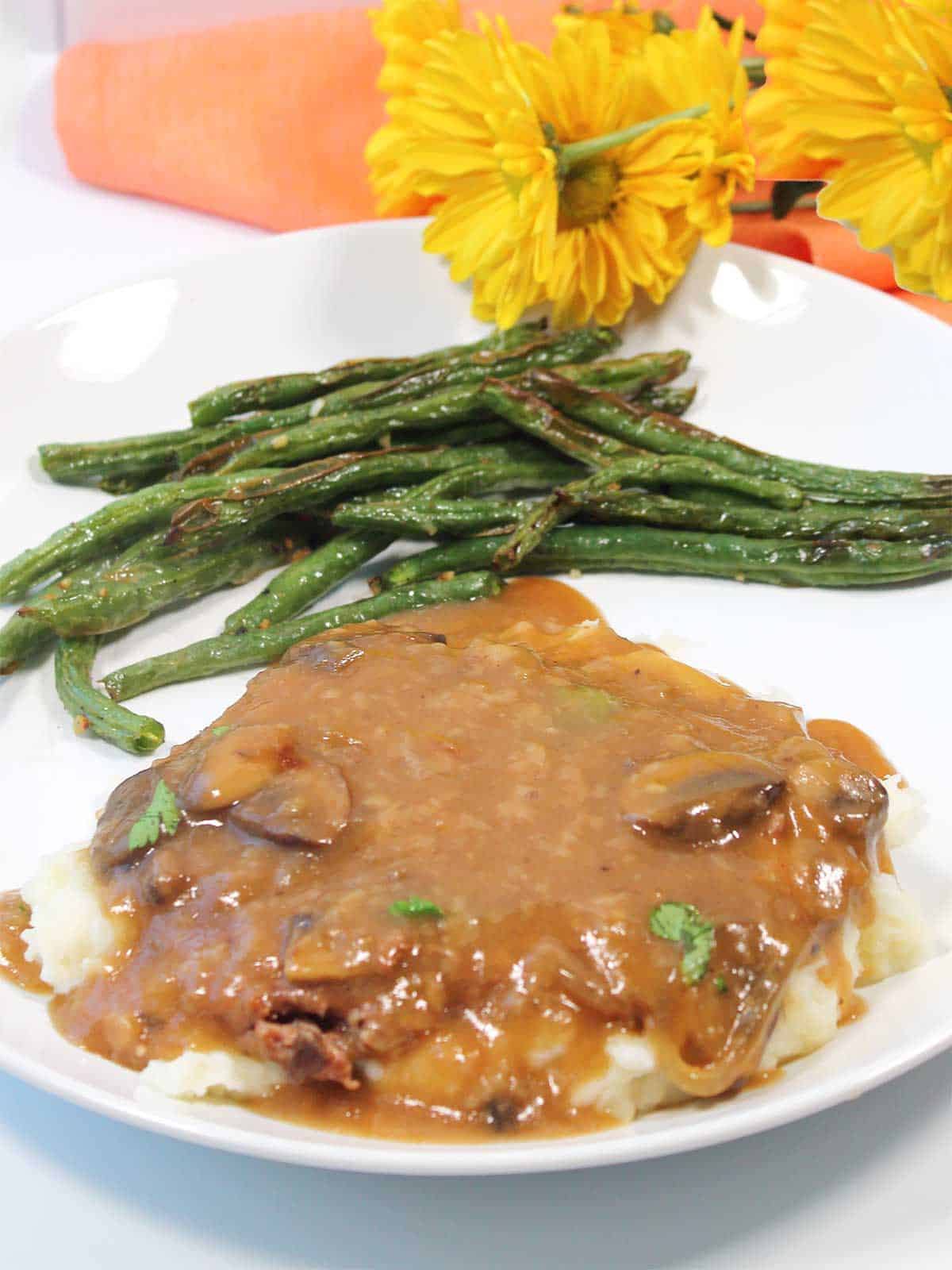 Plated crockpot cube steak with gravy on top of potatoes.
