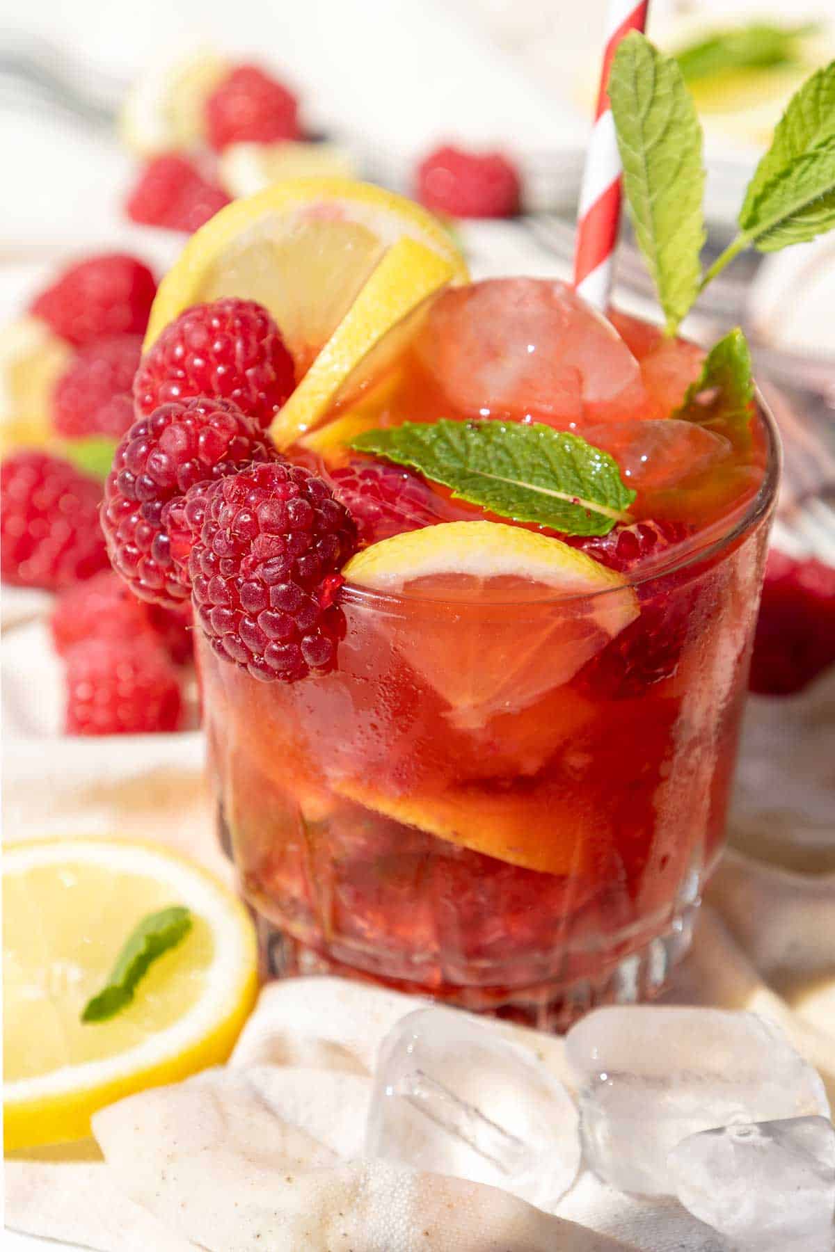 Closeup of raspberry mojito mocktail with mint sprig and straw.