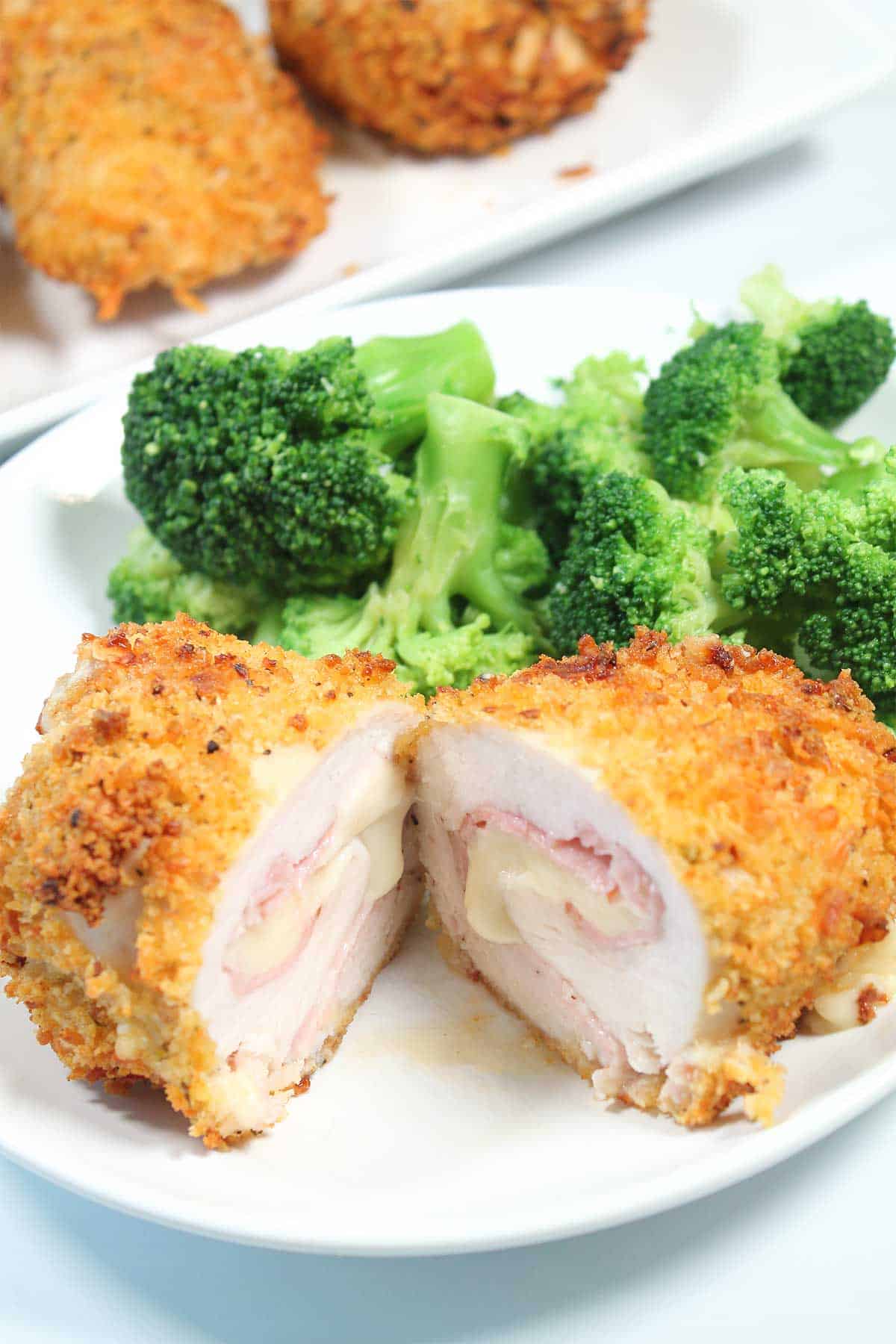 Chicken breast stuffed with ham and cheese halved on plate.