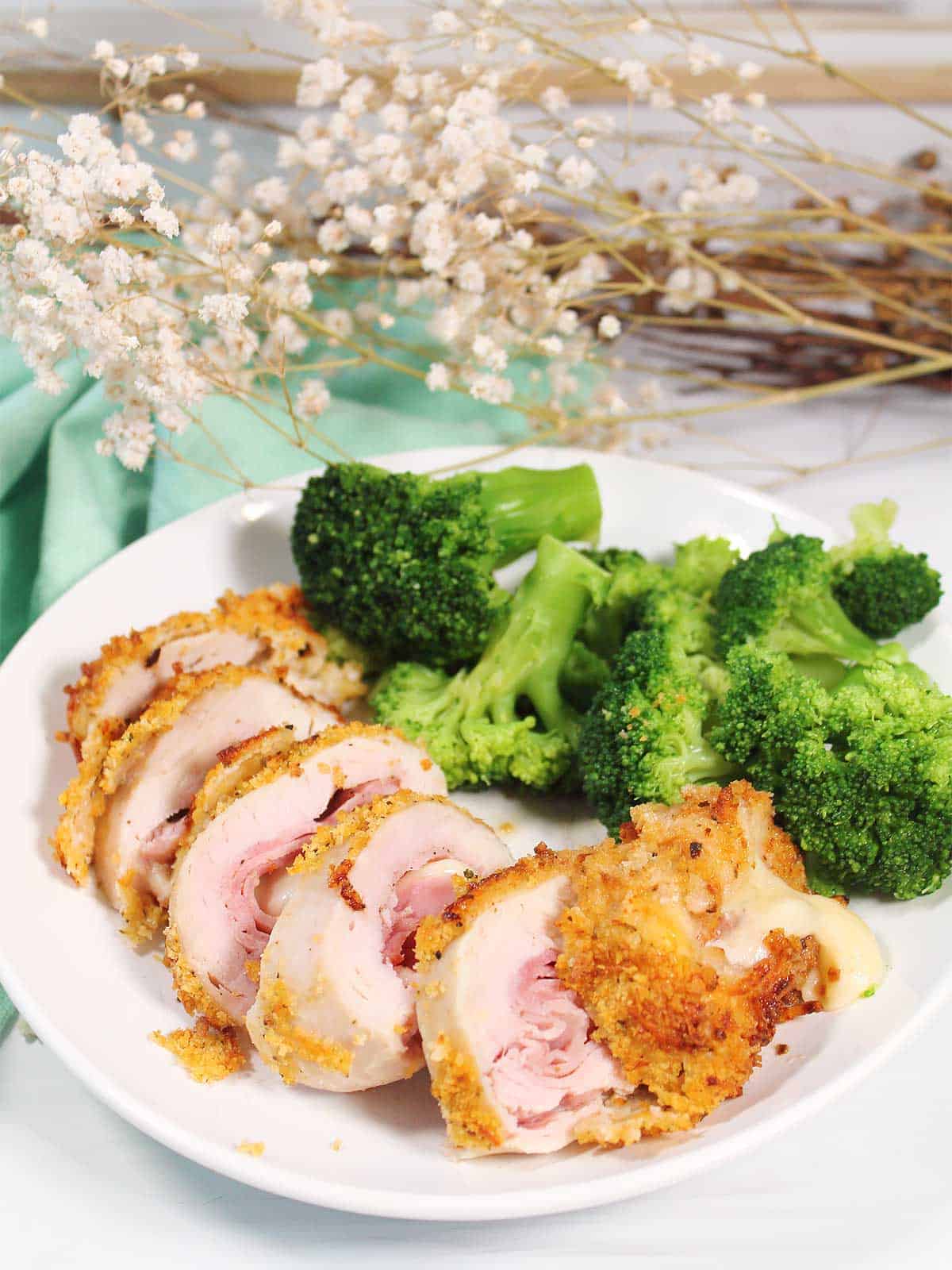 Sliced chicken cordon bleu plated with broccoli.