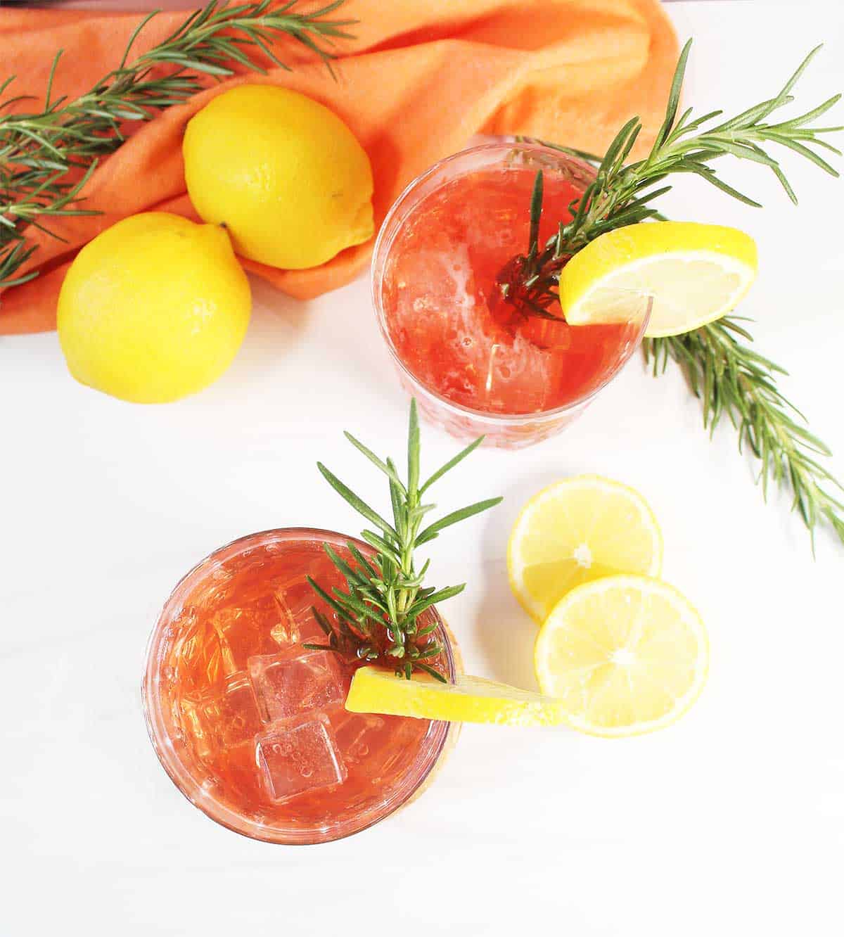 Overhead of two cocktails with lemon slice and rosemary garnish.