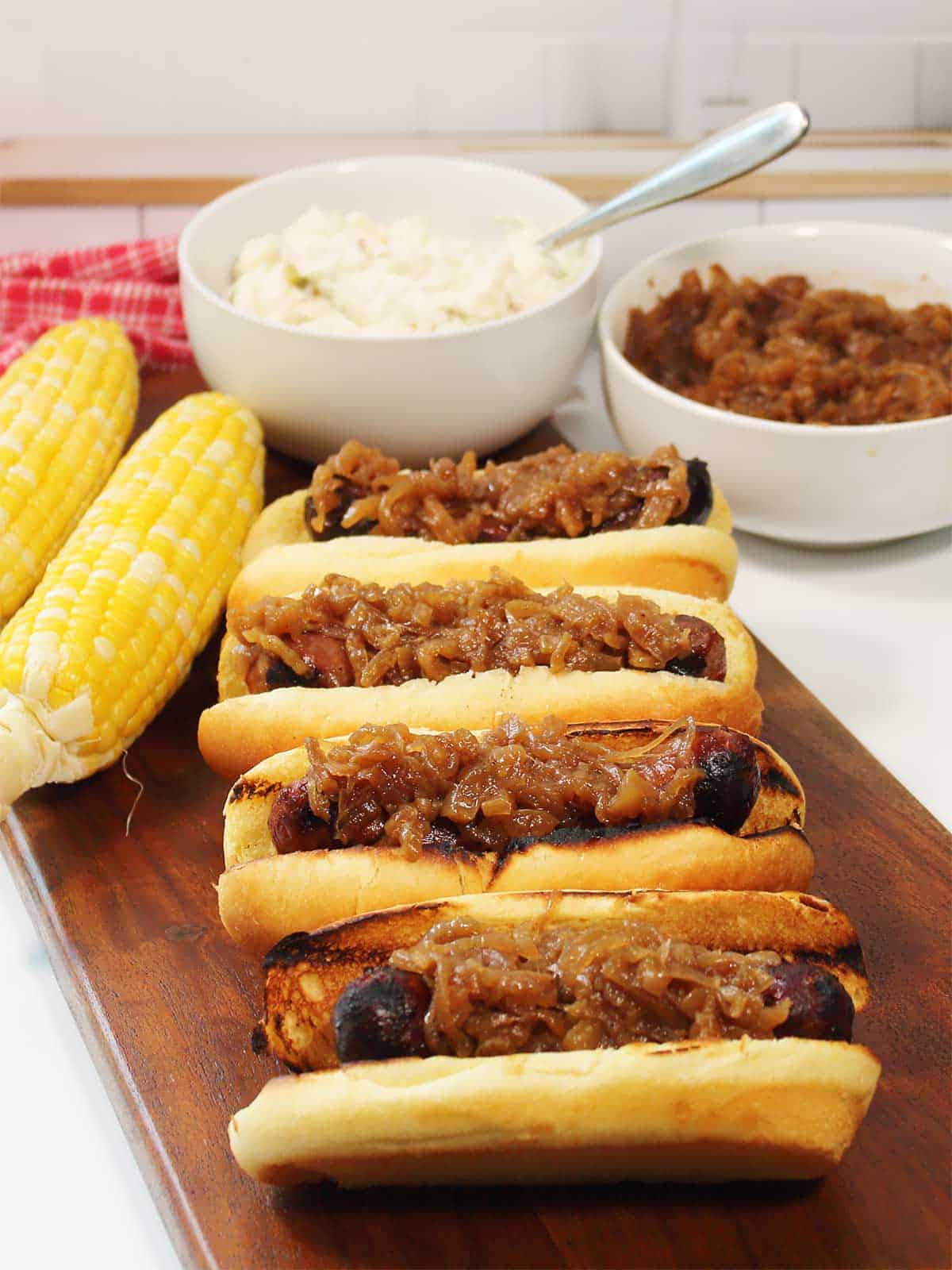 Grilled brats dinner with relish, corn and potato salad.