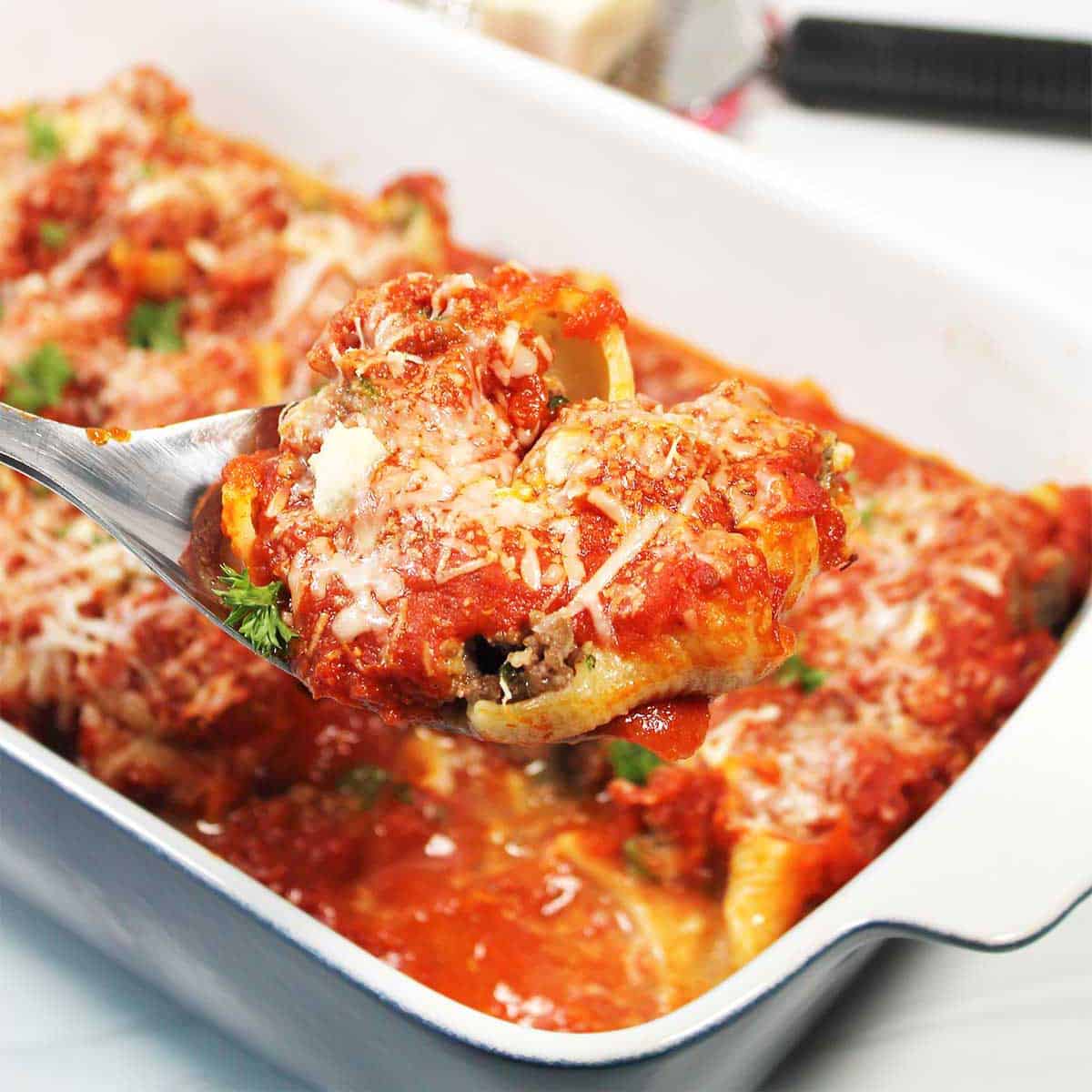 Stuffed Shells with ground beef on serving spoon.