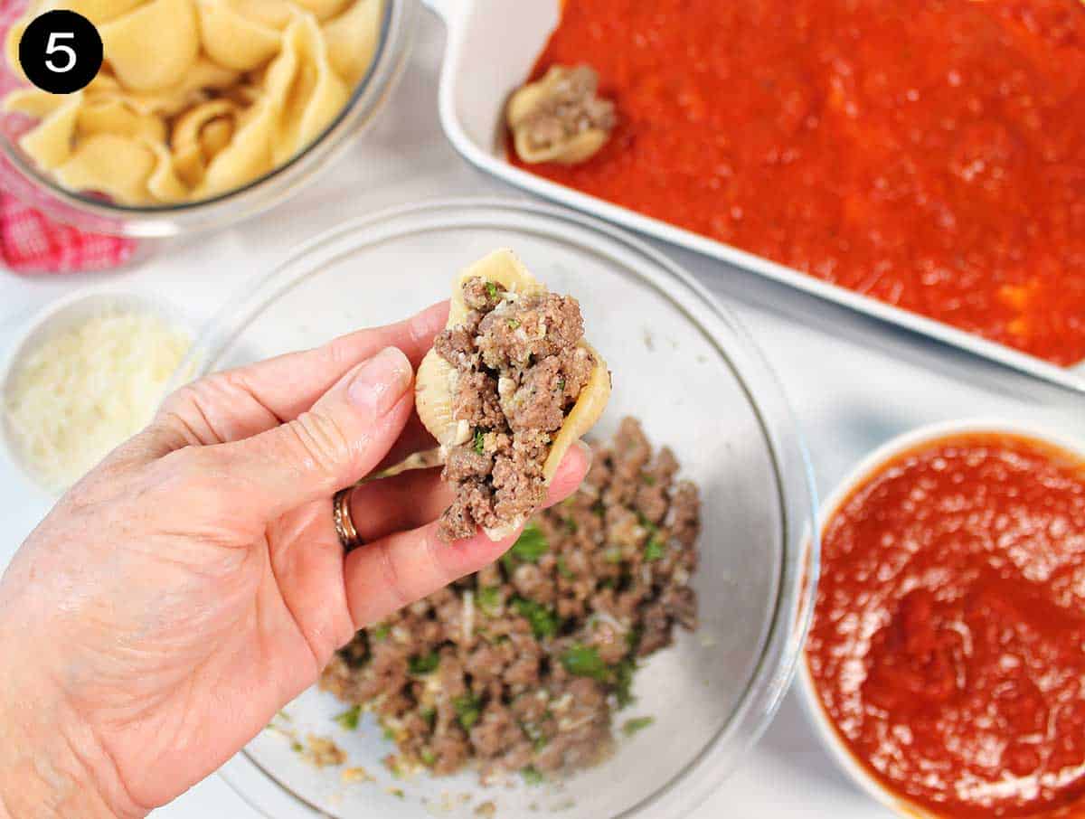 Stuffing pasta shells with ground beef.