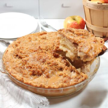 Closeup lifting slice of caramel apple crumble pie from pie dish.