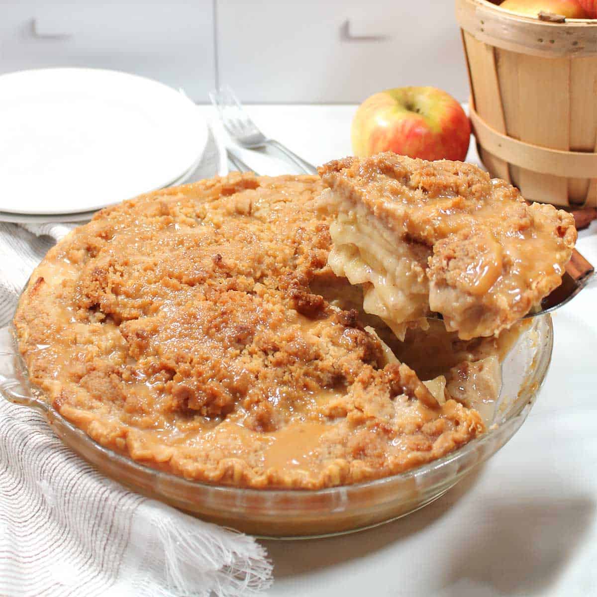 Closeup lifting slice of caramel apple crumble pie from pie dish.