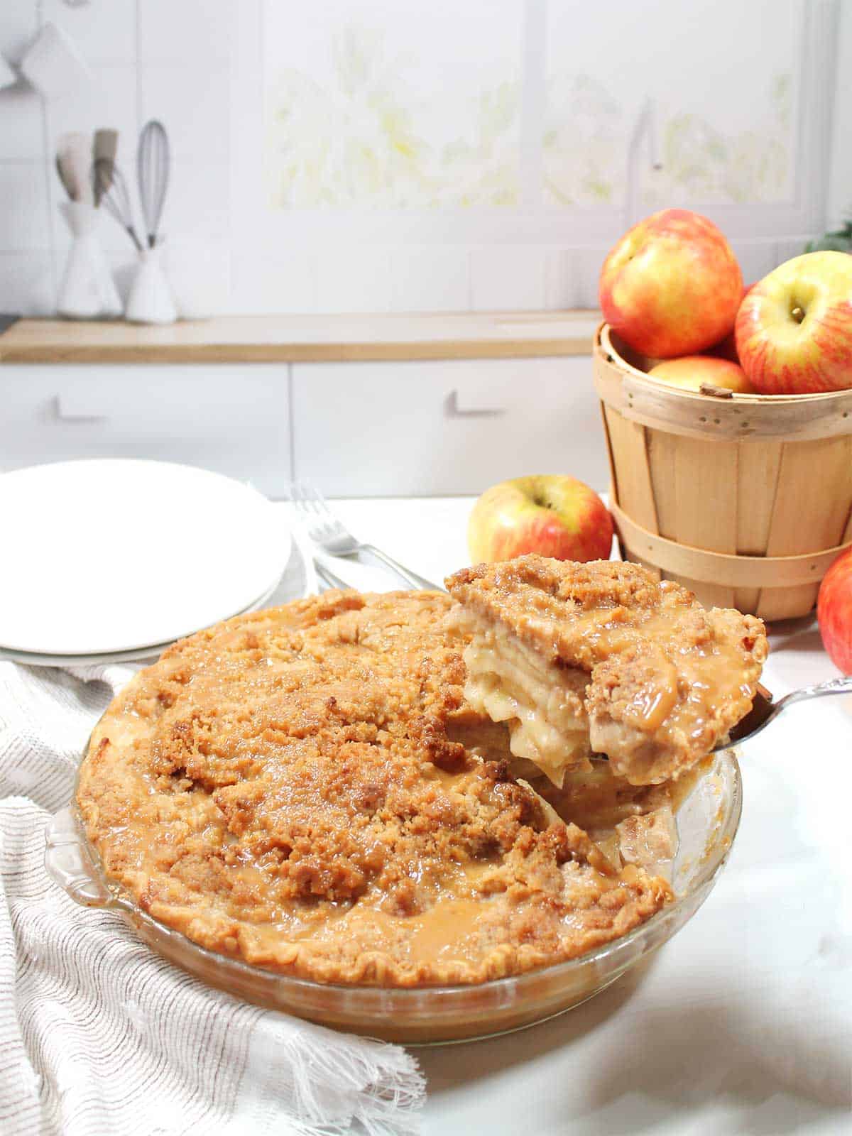 Lifting slice of caramel apple crumble pie from dish.