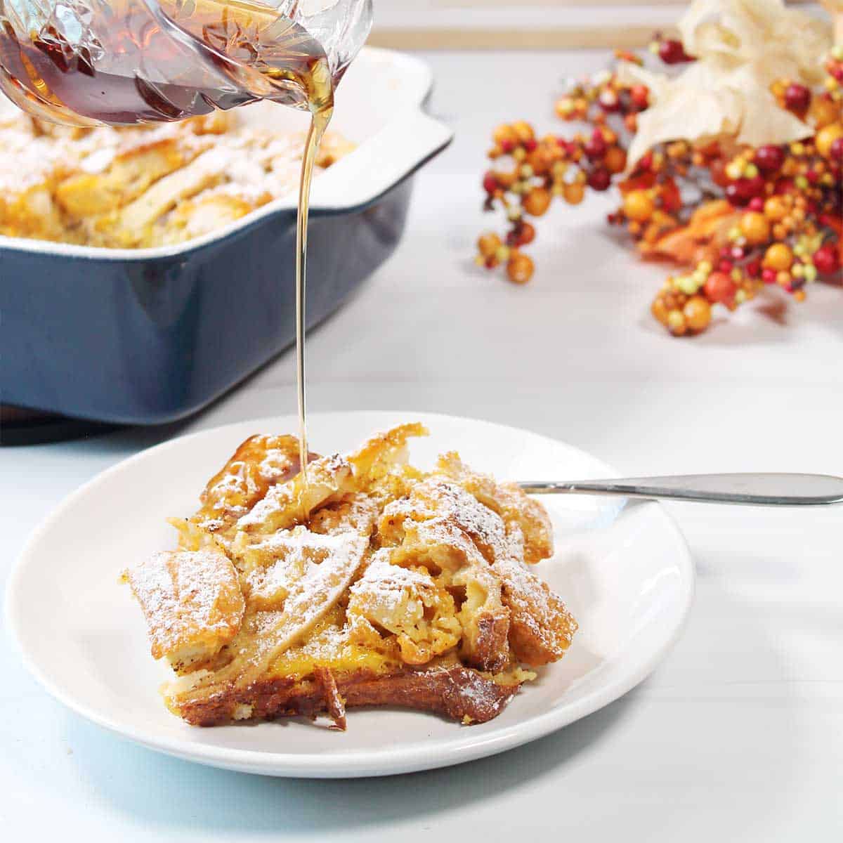 Drizzling plated serving of chicken and waffles casserole with maple syrup.