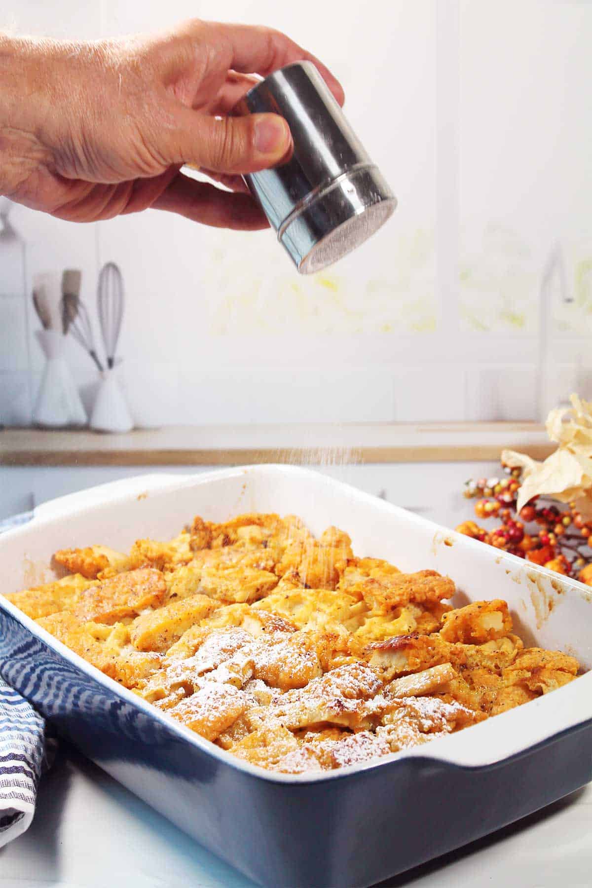 Shaking powdered sugar on baked casserole.
