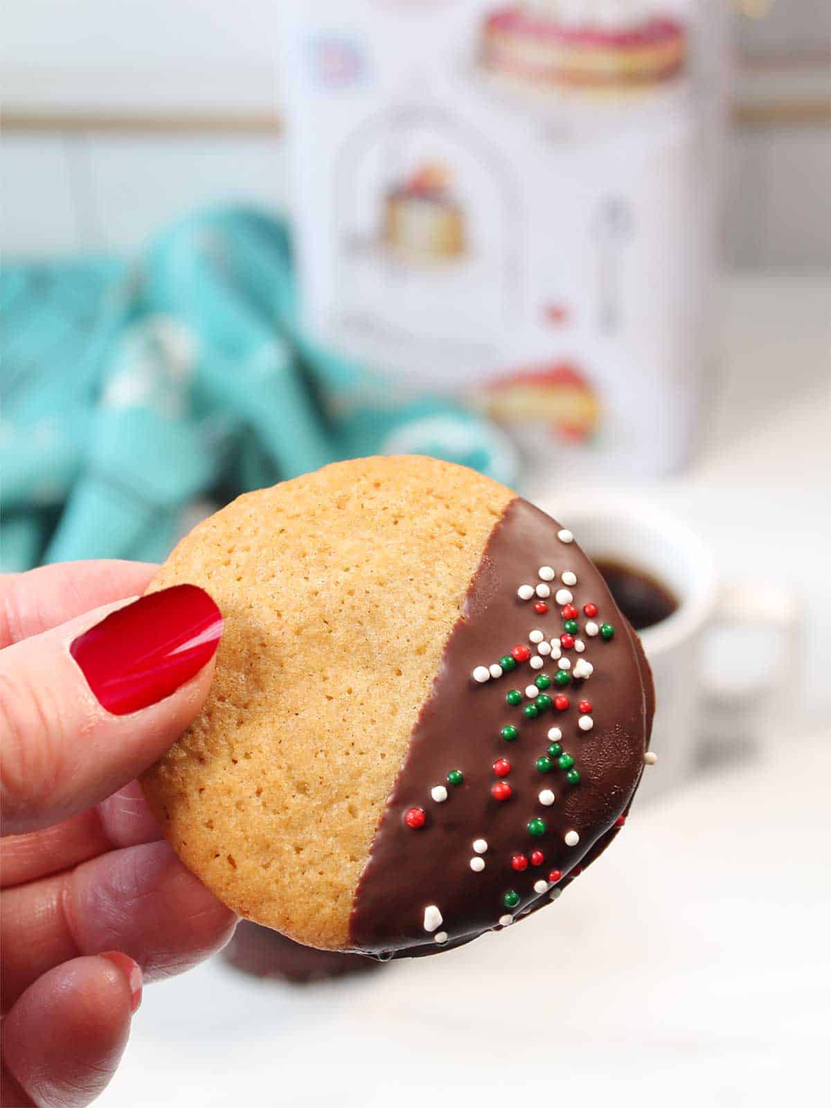 Holding a cookie showing chocolate dip and sprinkles.
