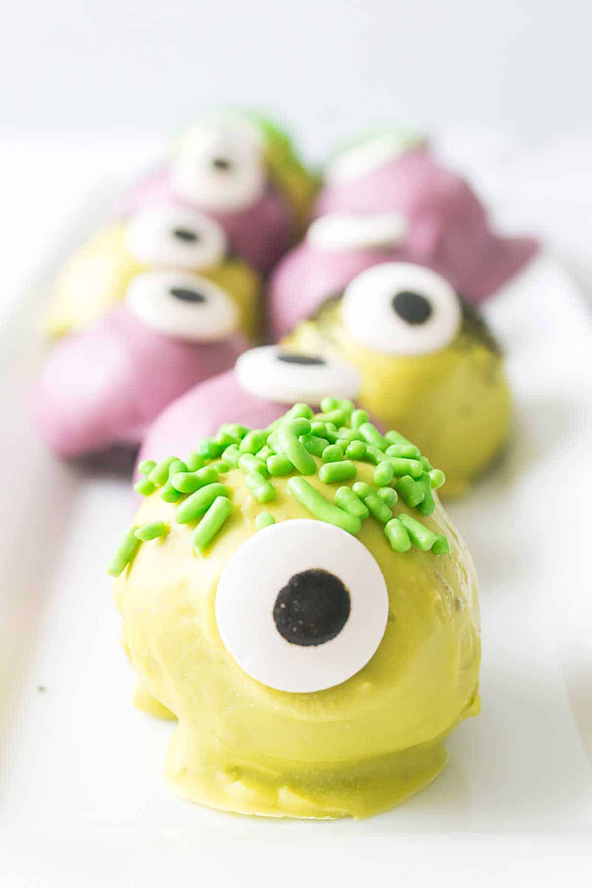 Halloween Monster Oreo Truffles on platter with yellow monster truffle in front.