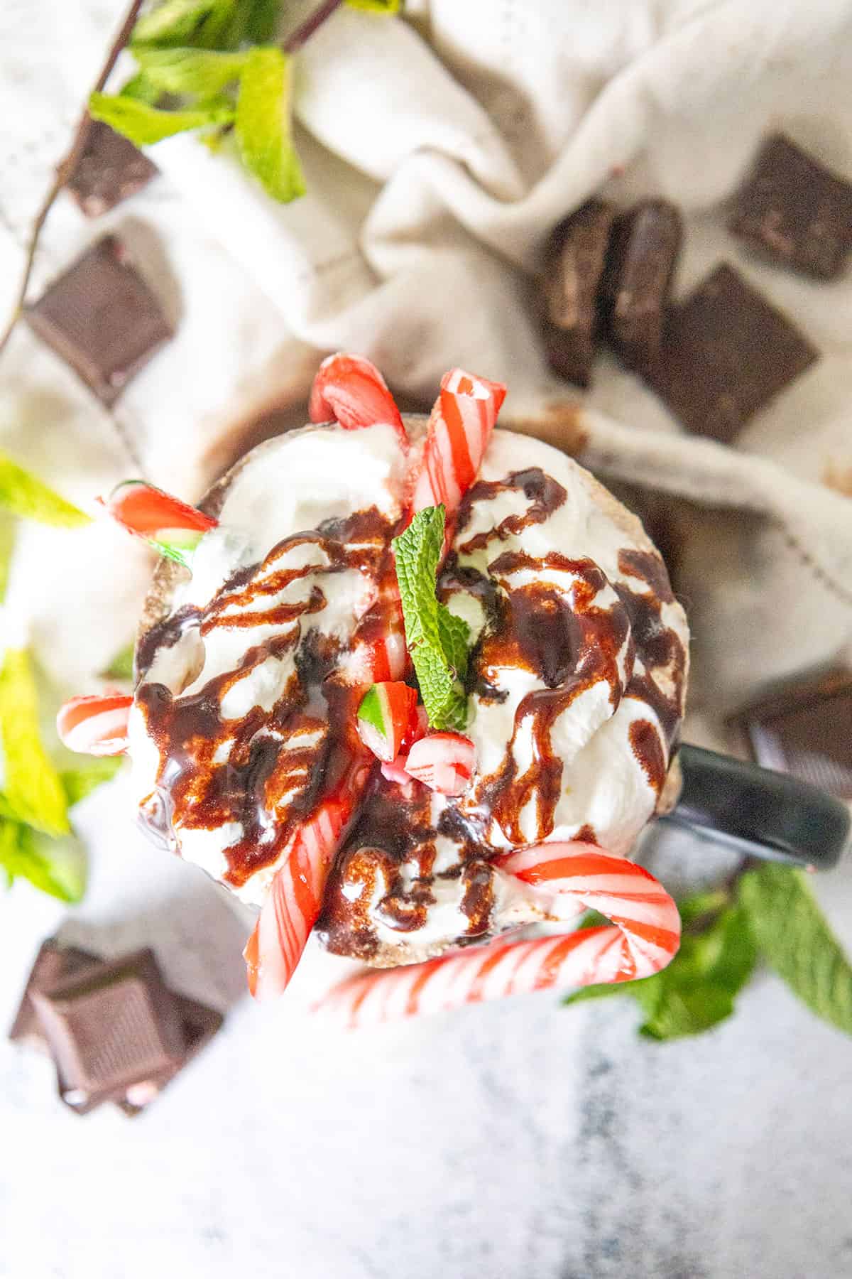 Overhead of hot chocolate with whipped cream and chocolate sauce.