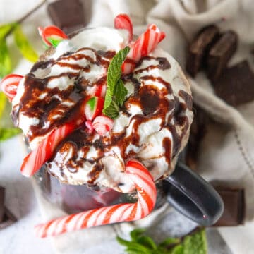 Overhead of peppermint hot chocolate showing whipped cream and chocolate sauce.