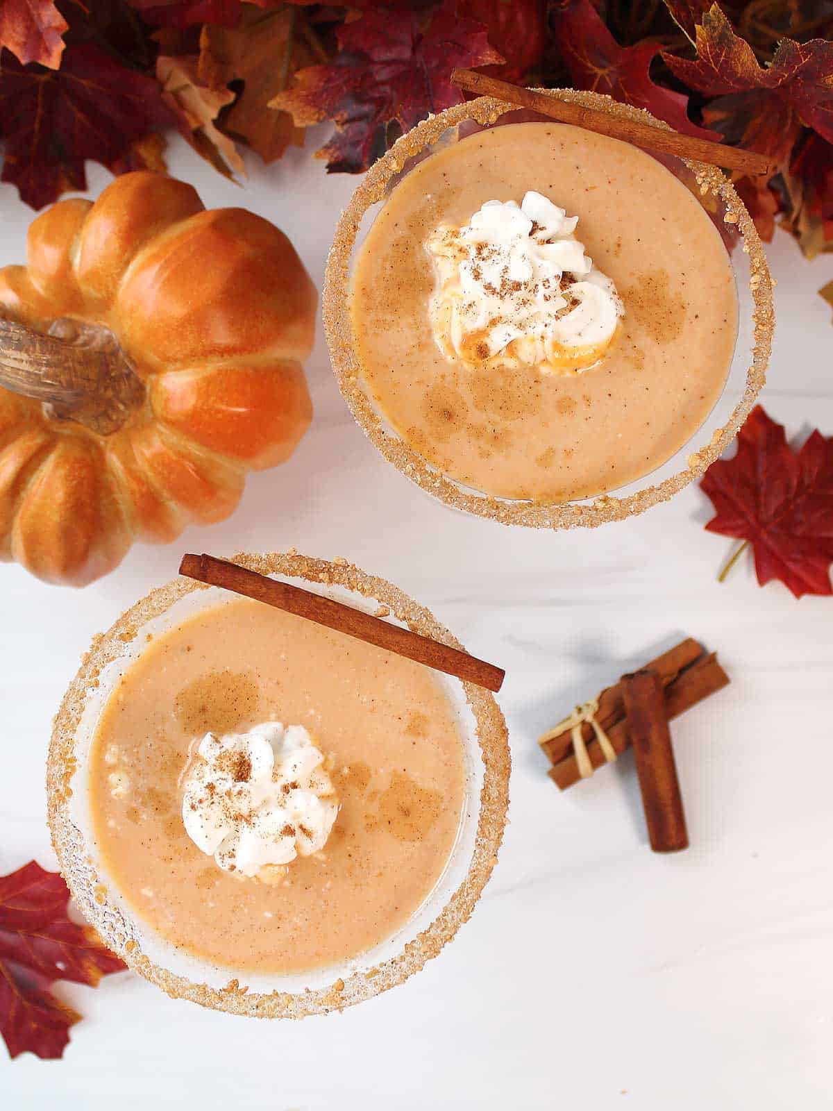 Overhead of two pumpkin pie martinis with whipped cream garnish.