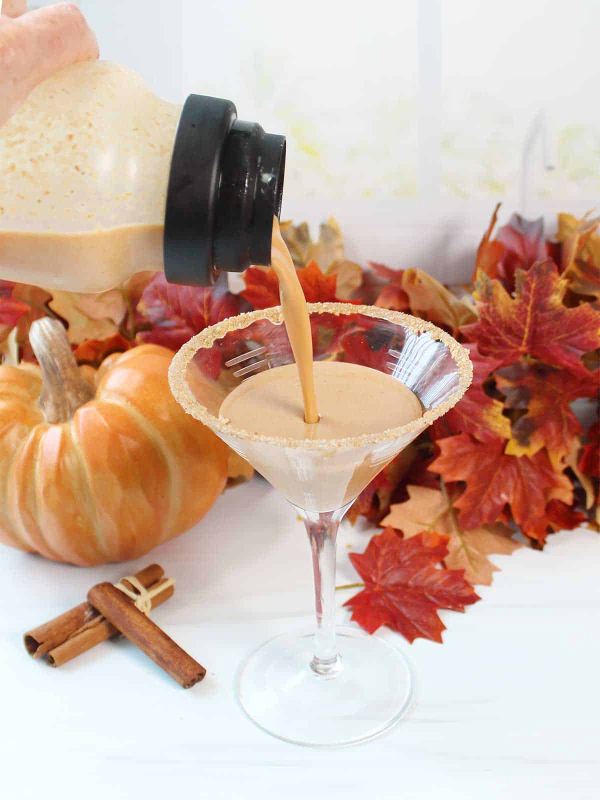 Pouring pumpkin pie martini into martini glass.
