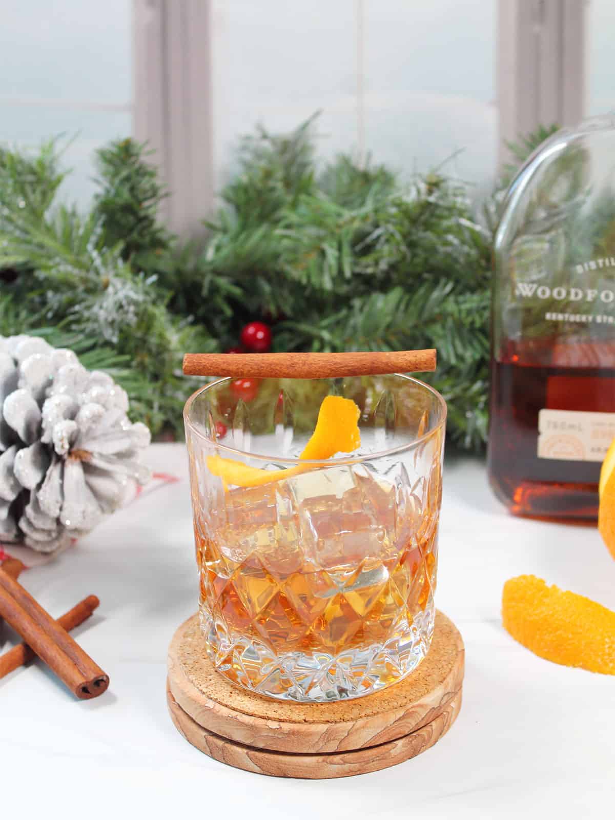 Finished cocktail with orange peel and cinnamon stick garnish.